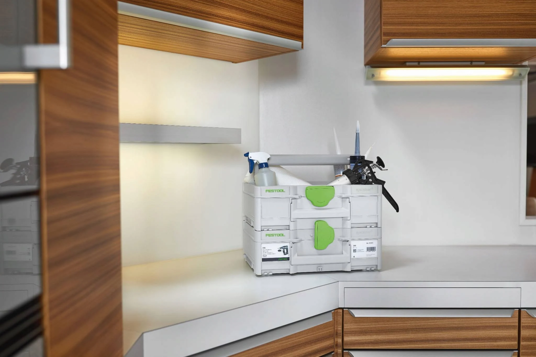 Scena di cucina con una valigetta portautensili FESTOOL su un bancone. Utensili e spray visibili.