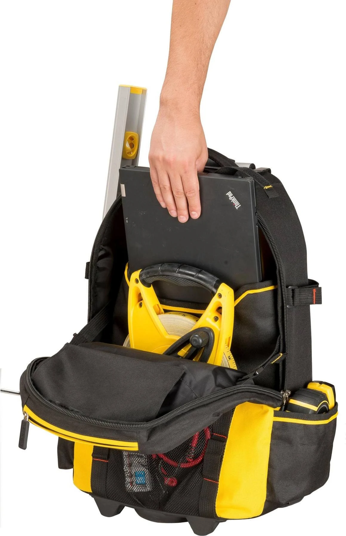 Una mano che raggiunge una borsa degli attrezzi contenente un laptop, una livella e un metro a nastro.
