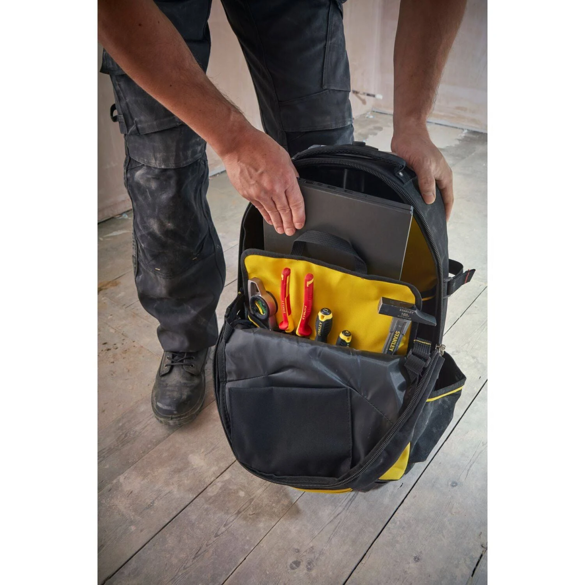 Una persona tiene in mano una borsa porta attrezzi Stanley nera e gialla.