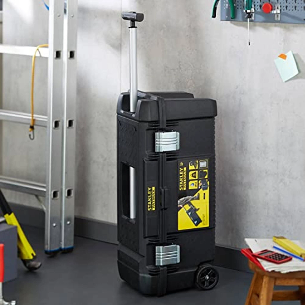 Cassetta portautensili Stanley FatMax nera con ruote. Scala e attrezzi sullo sfondo su una parete del garage.