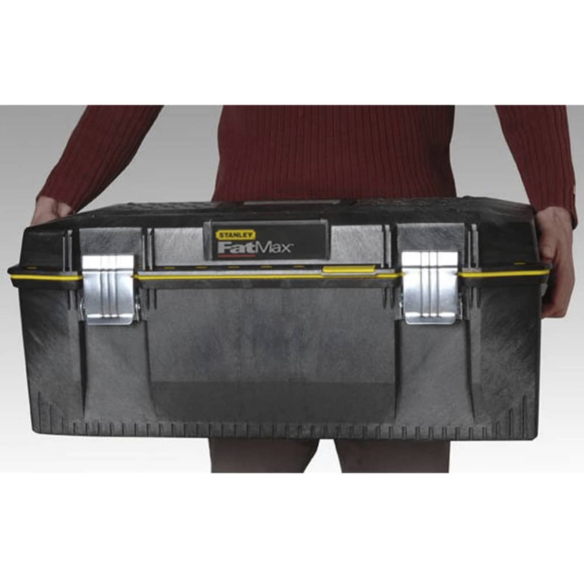 Una persona sosteniendo una caja de herramientas Stanley FatMax negra con acentos amarillos.