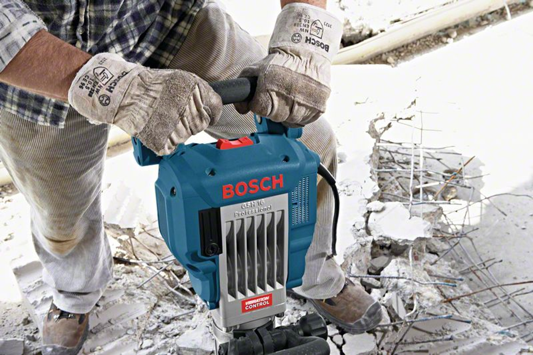 Un hombre con guantes usa un martillo demoledor Bosch. La herramienta es azul y el hombre trabaja afuera.
