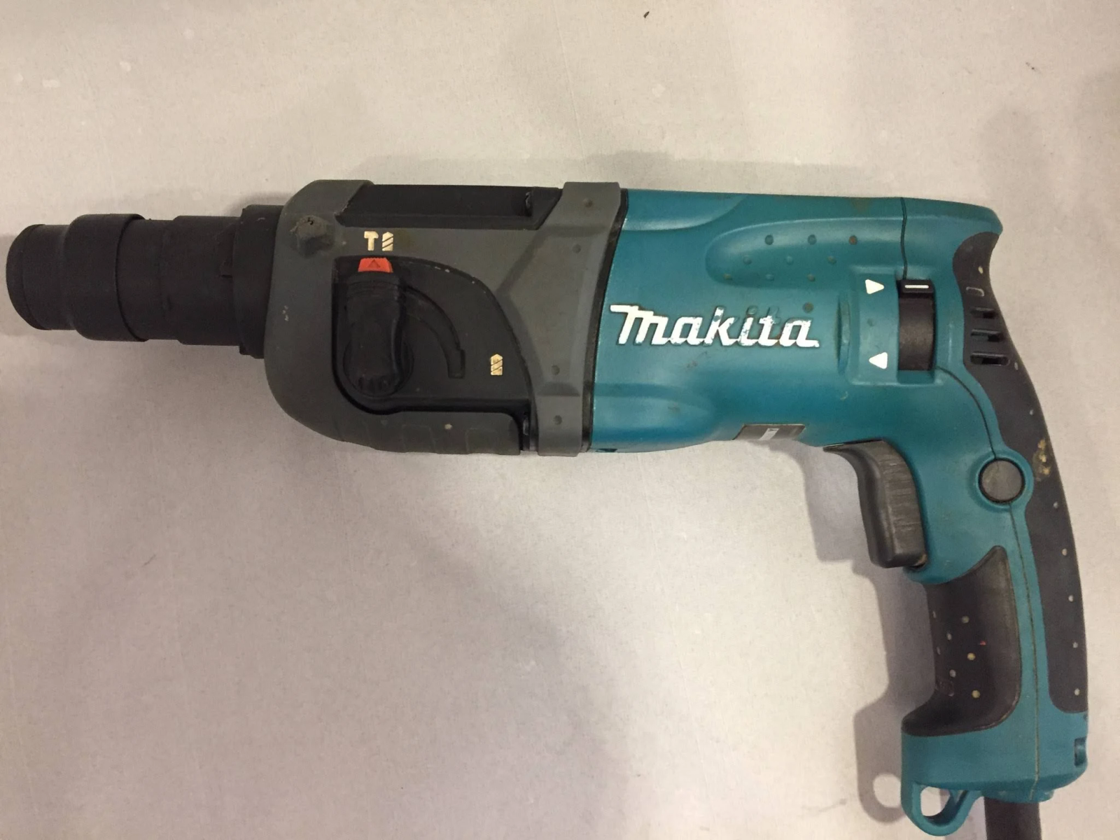 Un taladro percutor Makita turquesa y gris se ve desde arriba, sobre un fondo blanco.