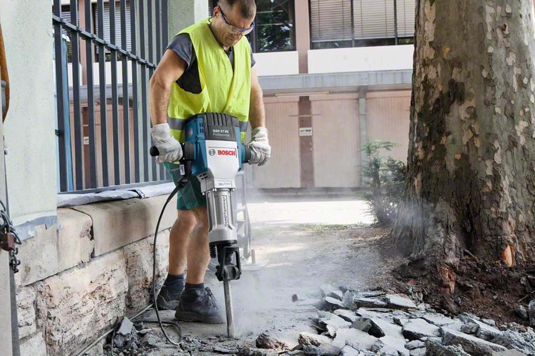 Bir inşaat işçisi bir Bosch yıkım çekici kullanıyor. Betonu kırıyor.