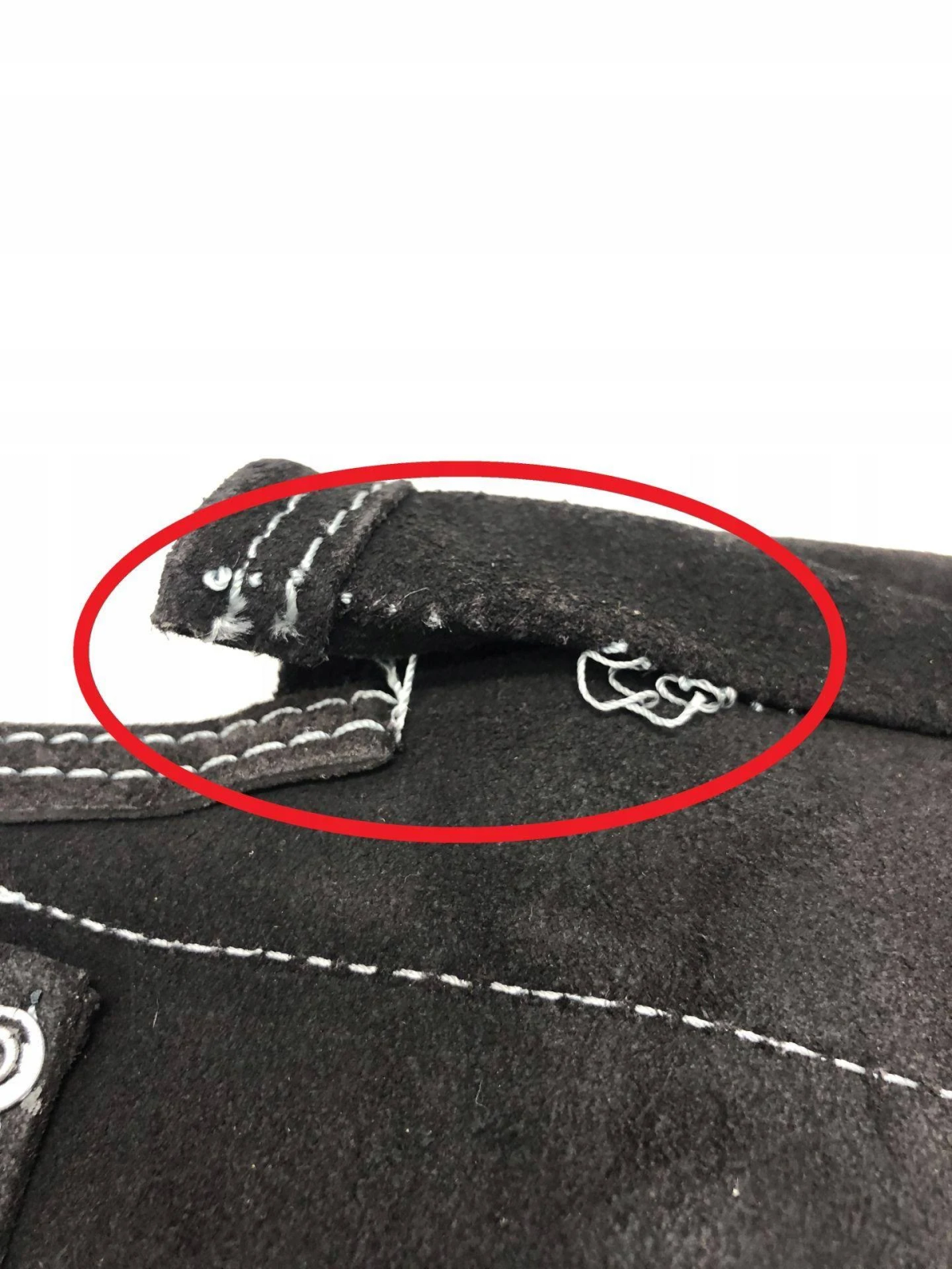 Primer plano de una tela negra. La tela está cosida con hilo blanco y tiene un círculo rojo alrededor.