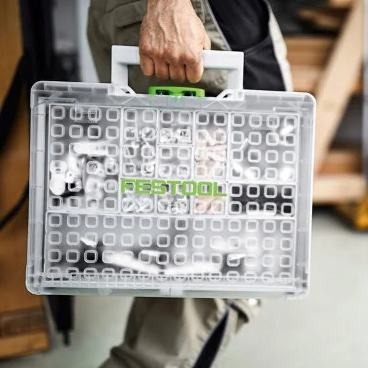 Valigetta per utensili in plastica trasparente con utensili, manico e logo verde visibili.
