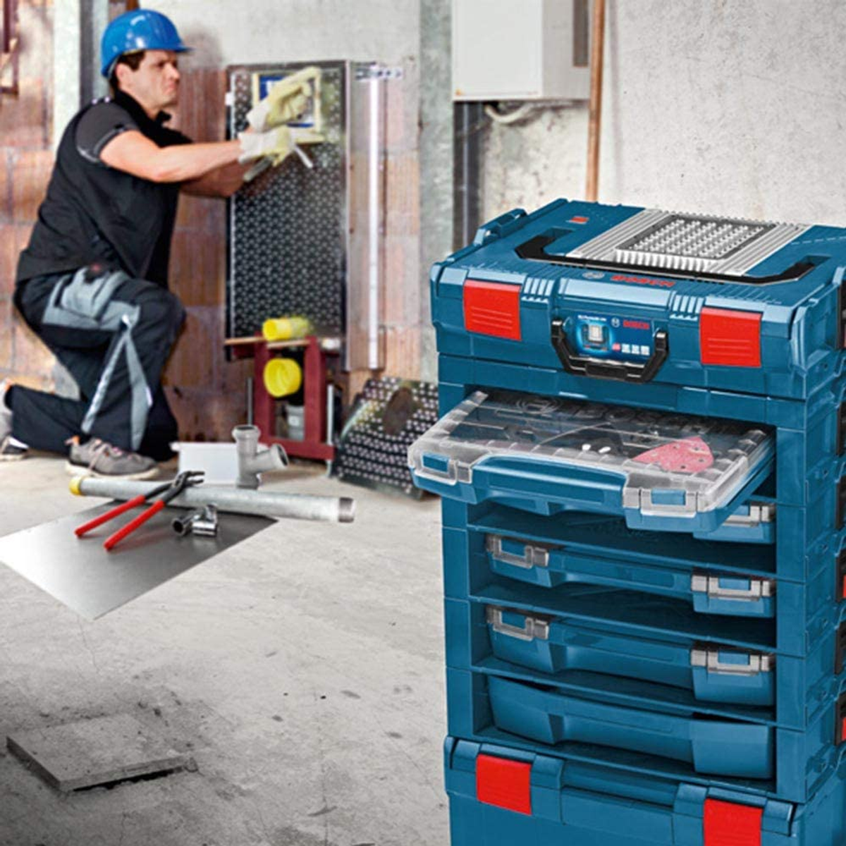 Un operaio installa attrezzi in una cassetta degli attrezzi blu. Un'altra cassetta degli attrezzi è visibile sullo sfondo.