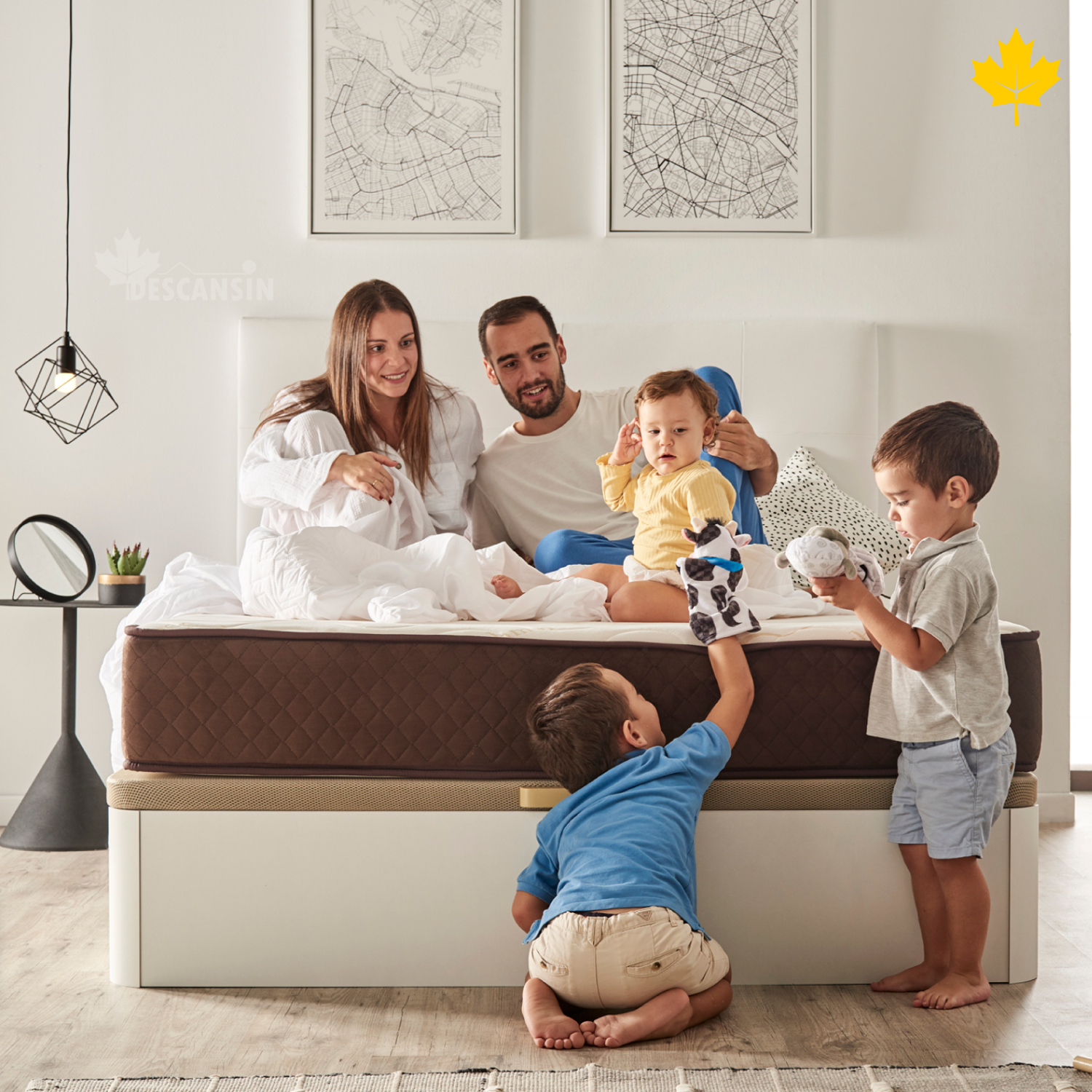 Familia en una cama con niños. Dos adultos y dos niños están en una cama con un colchón marrón, jugando con juguetes.