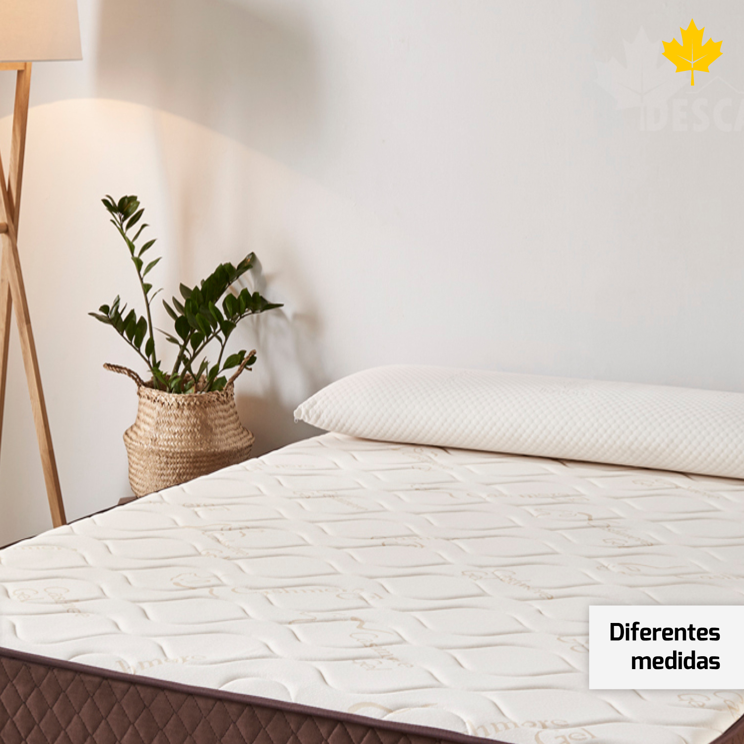 Una cama con colchón, almohada y una planta en una cesta sobre fondo blanco.