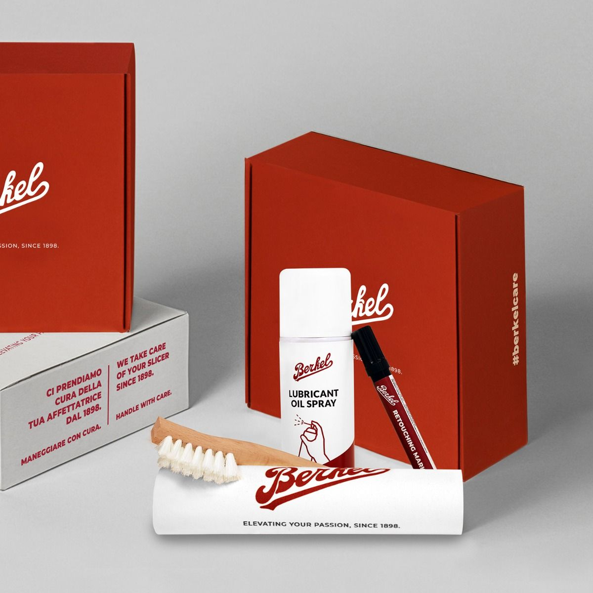 Scatole rosse, un flacone spray bianco, un pennarello nero e una spazzola su una superficie grigia.