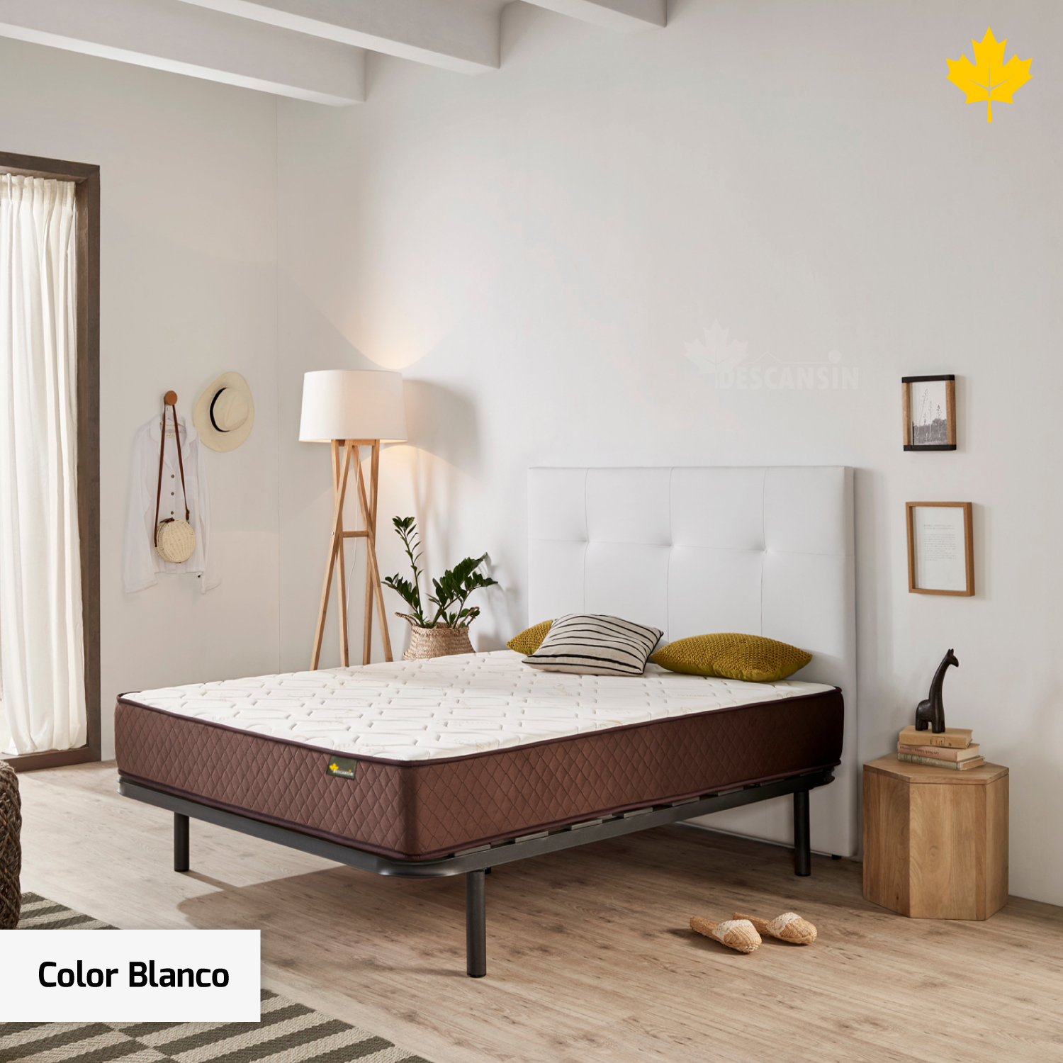 Dormitorio con cabecero blanco y colchón marrón. Mesita de noche de madera, lámpara y alfombra a rayas.