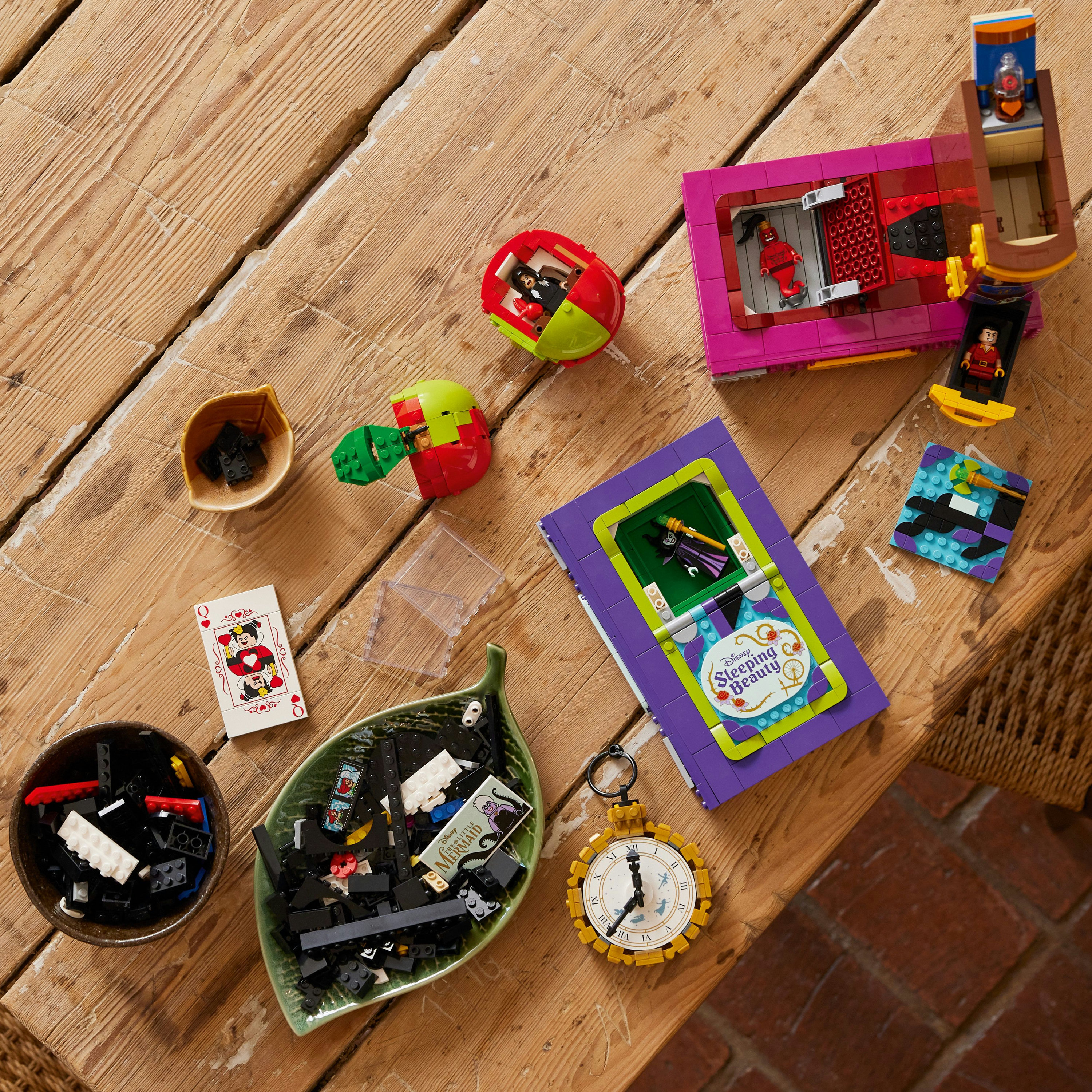Pièces Lego éparpillées sur une table en bois. Figurines, un livre, une horloge et divers éléments.