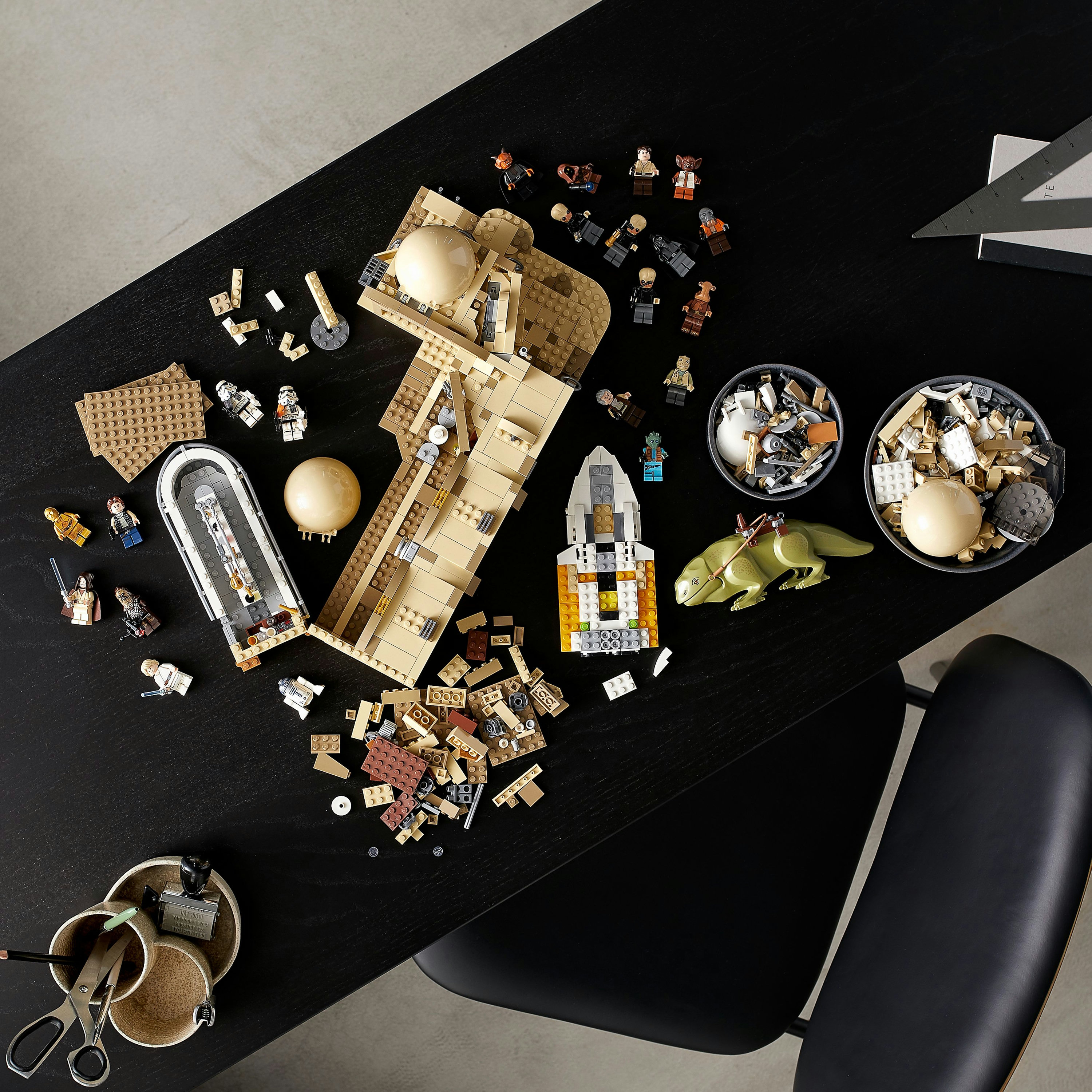 Zestaw Lego Star Wars, części rozłożone na czarnym stole z figurkami.