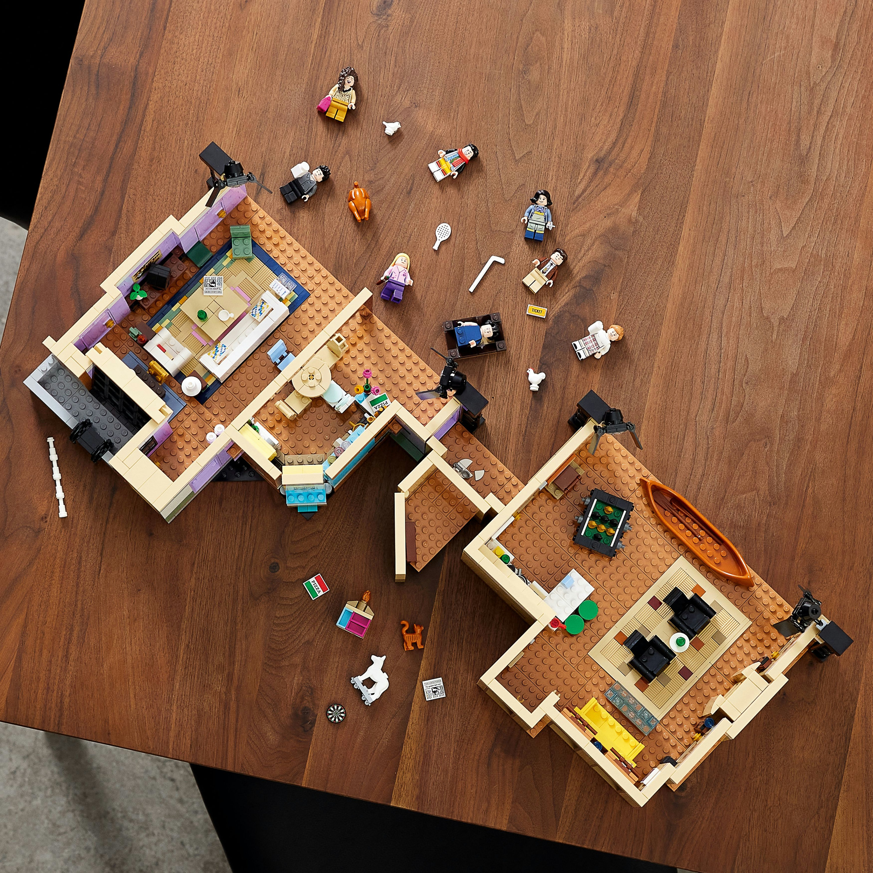 Ahşap bir masaya yerleştirilmiş, mini figürlü bir ev Lego seti.