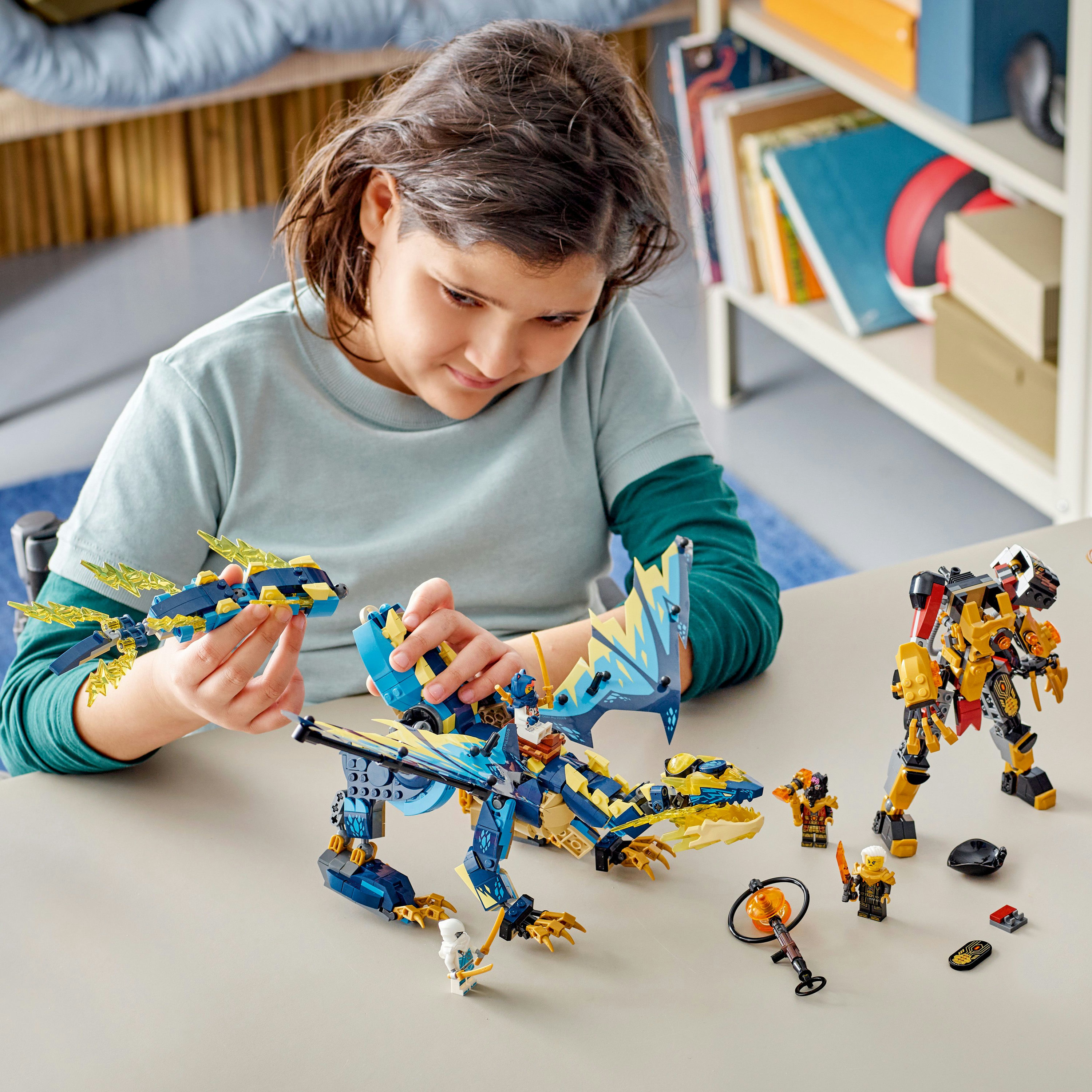 Une fille jouant avec des sets Lego Ninjago. Comprend un dragon, un mech et des figurines.