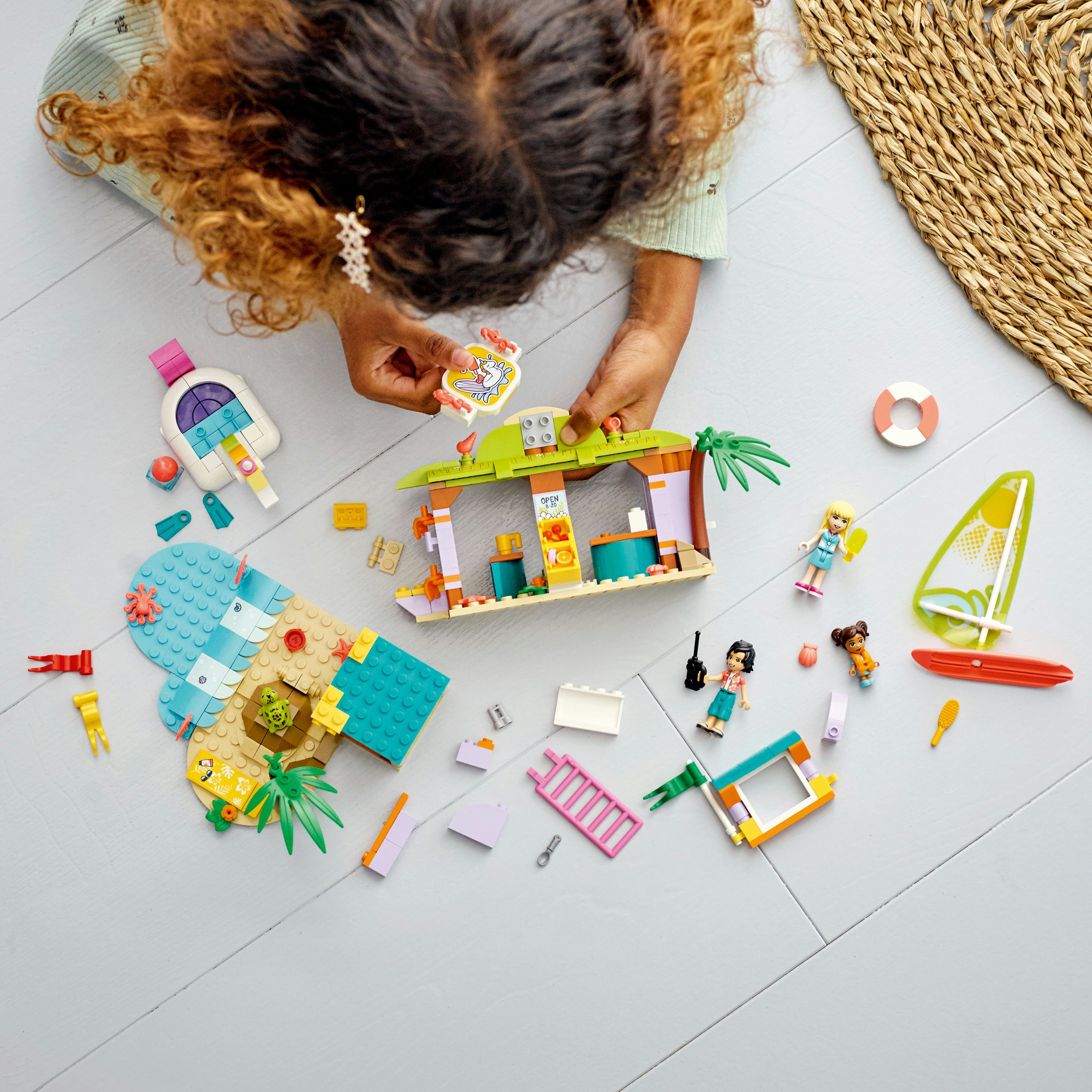 Un enfant joue avec des LEGO, construisant une scène de plage avec des figurines et accessoires.