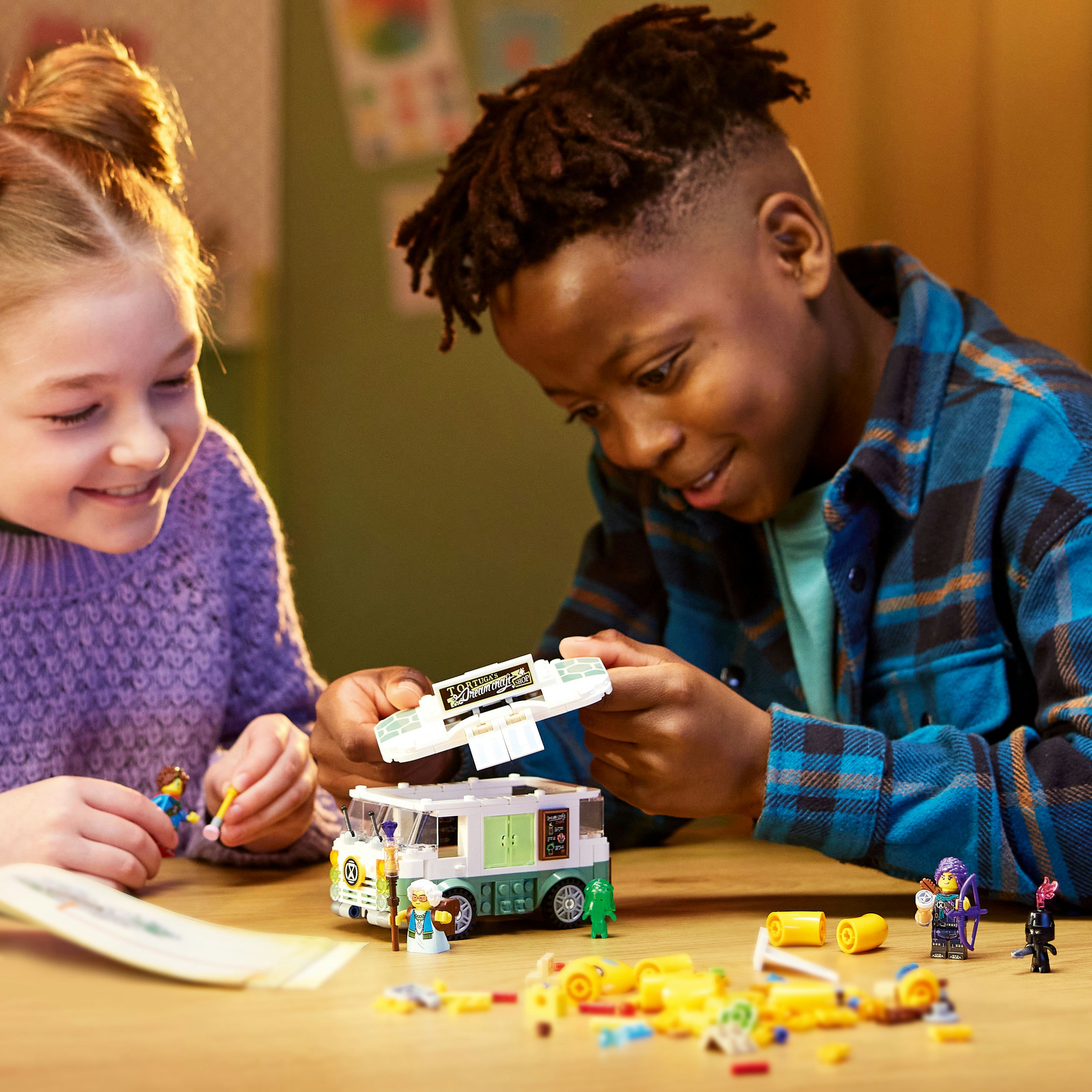 Zwei Kinder spielen mit einem Lego-Set. Ein Kind hält eine Minifigur und ein Lego-Teil.