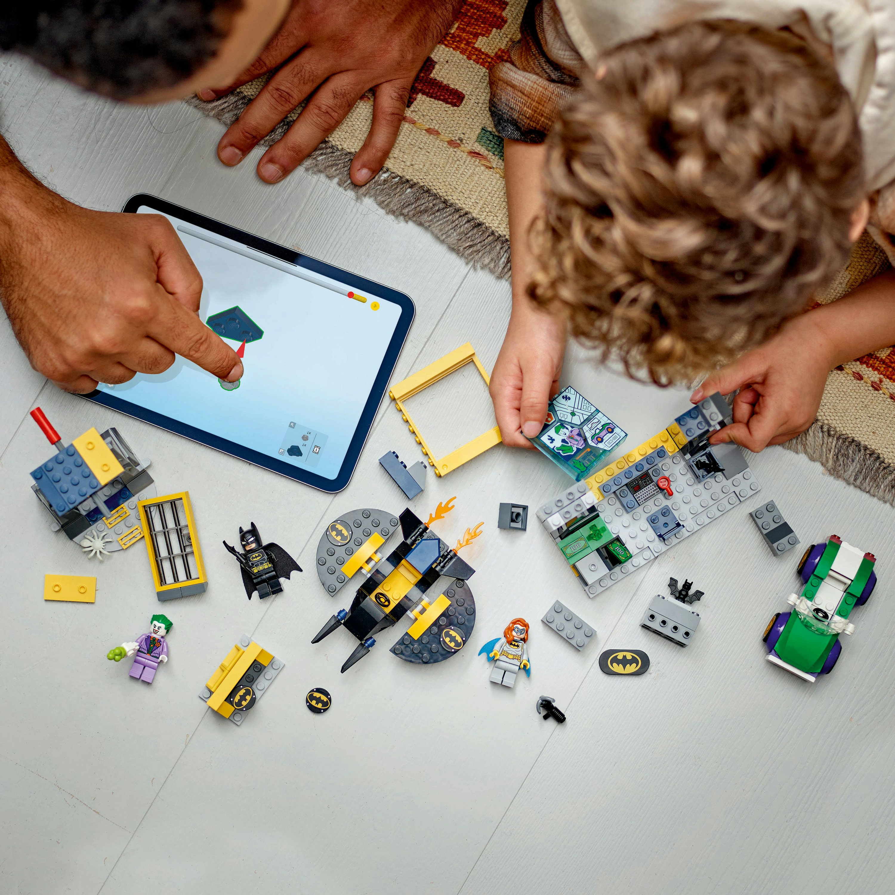 Draufsicht auf Kinder und Erwachsene, die mit Lego Batman und anderen Lego-Teilen spielen.