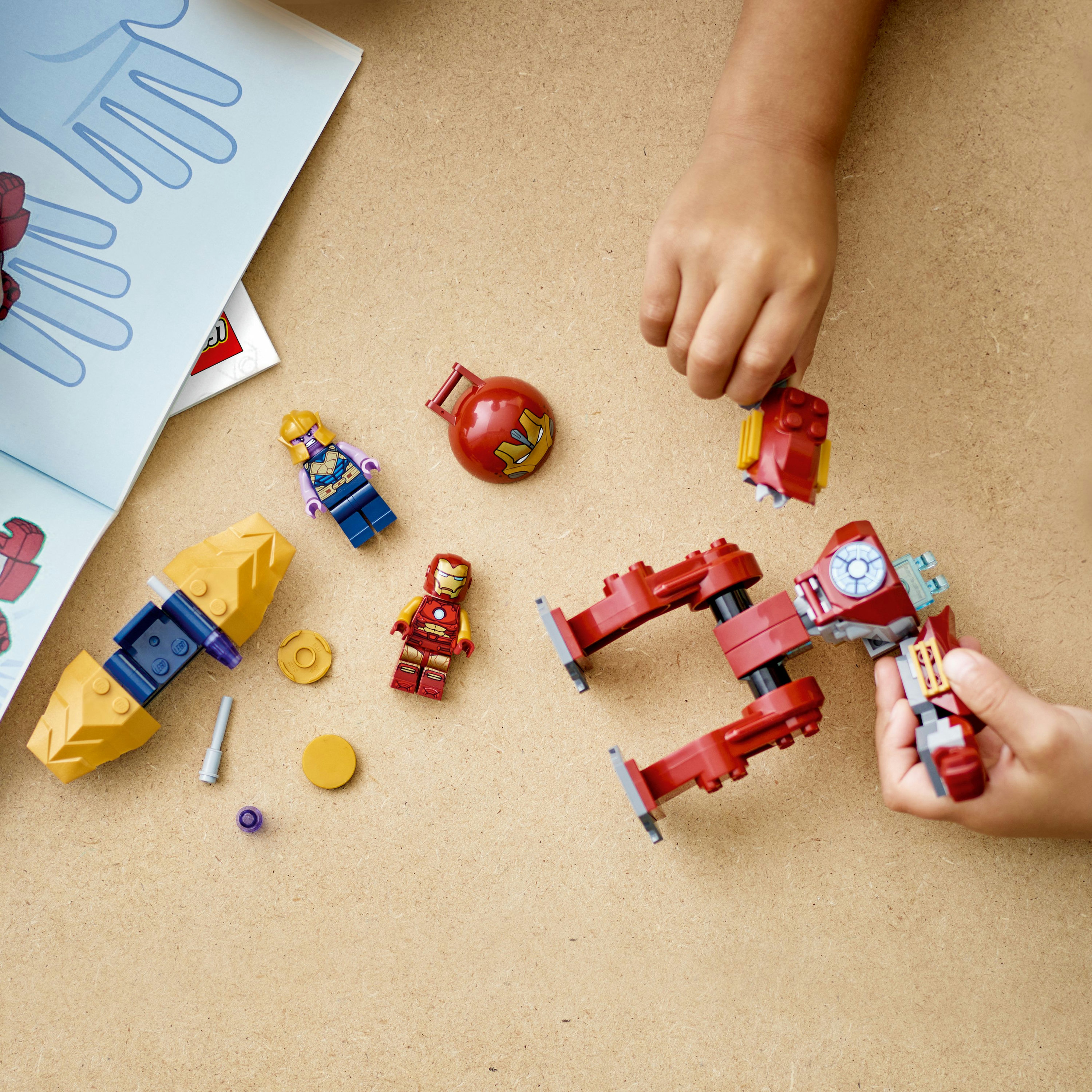 Lego-Set mit Iron Man- und Thanos-Figuren und -Teilen auf brauner Oberfläche.
