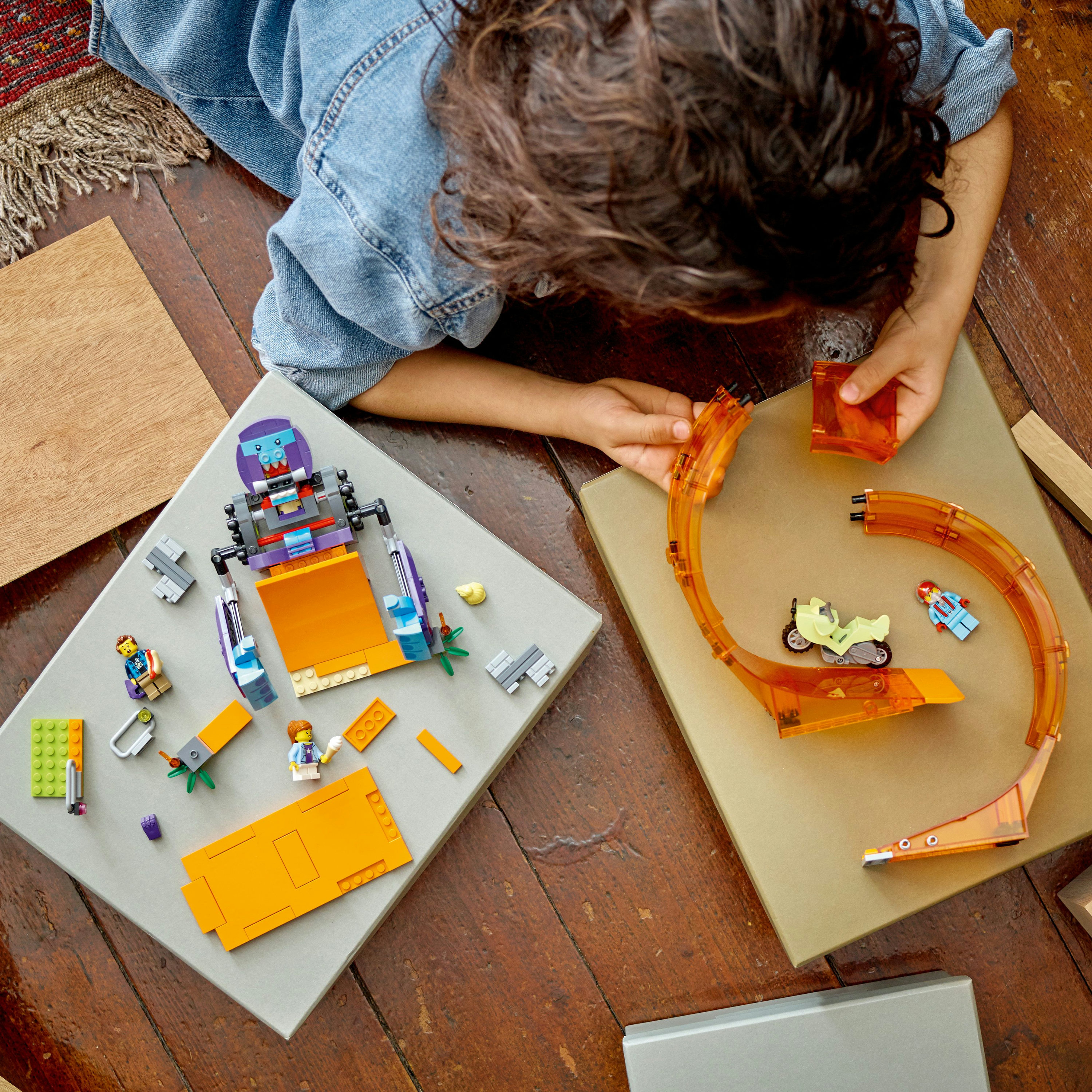 Kind dat met een Lego-set speelt, een speelgoedrobot en een racebaan bouwt.