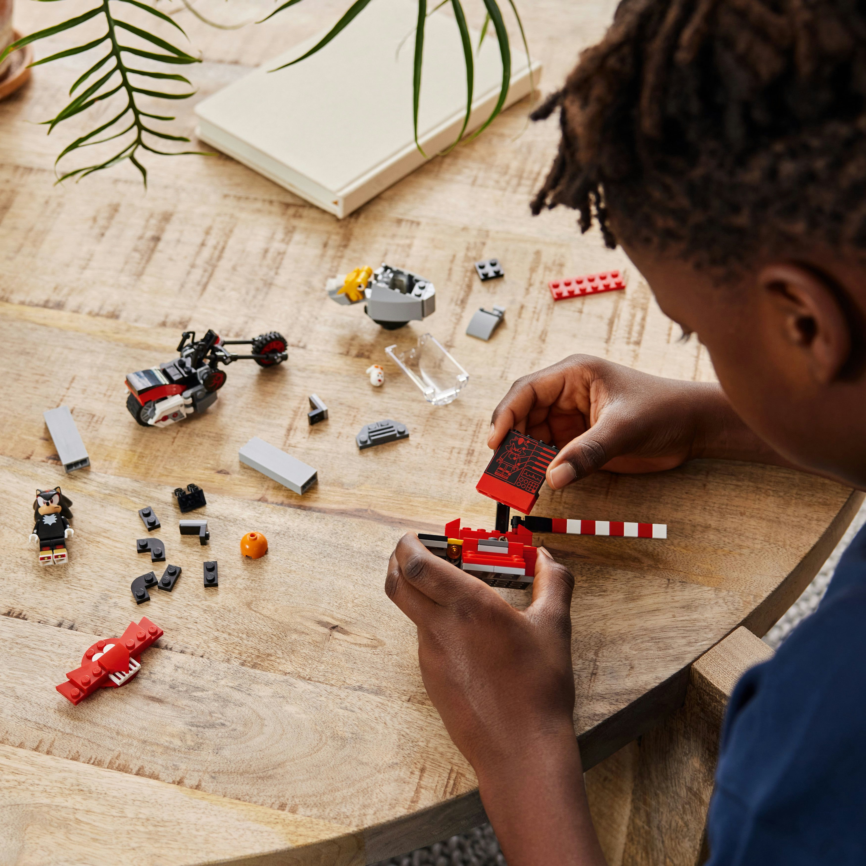 Ein Kind baut Lego auf einem Holztisch zusammen.