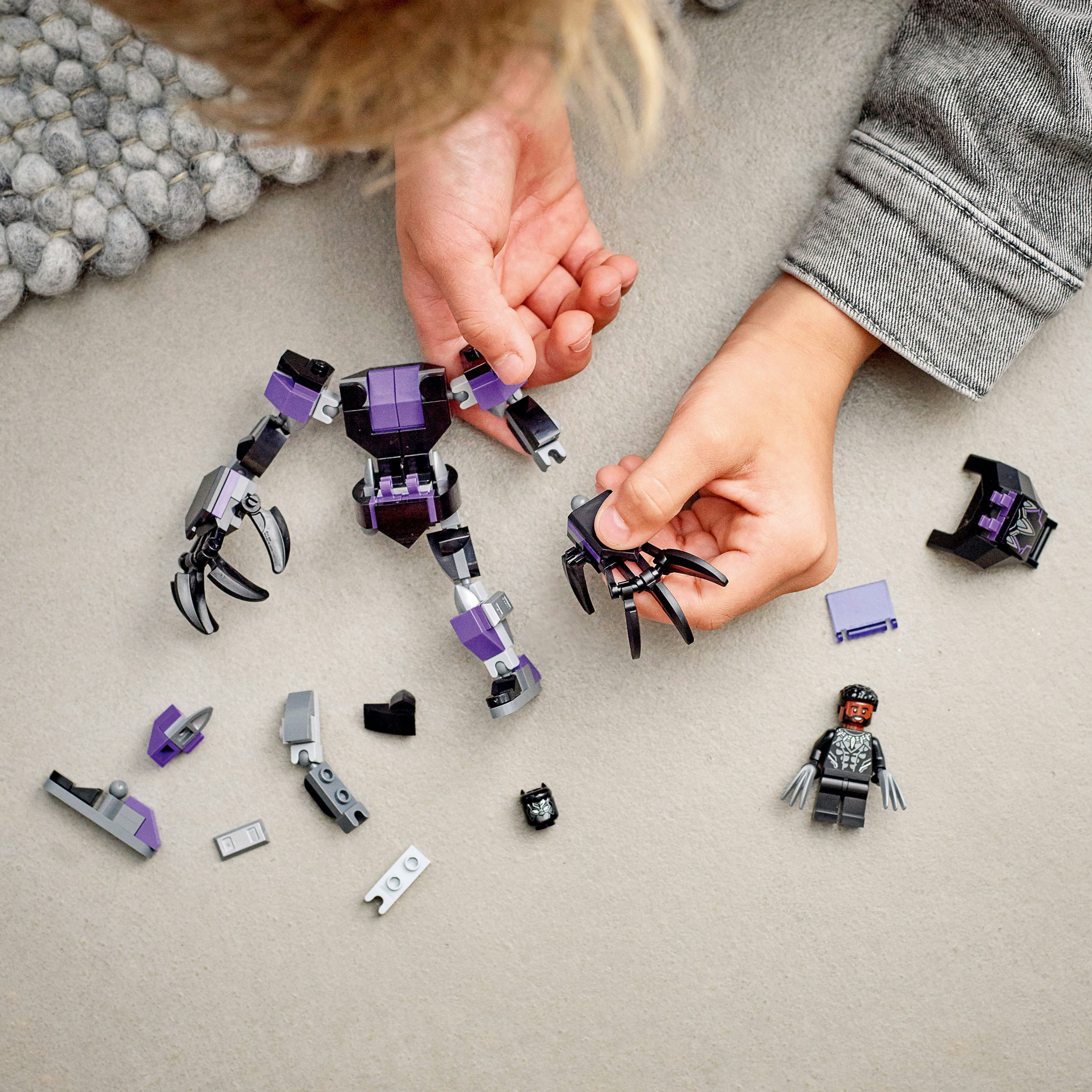 Hände montieren einen Lego Black Panther Mech. Teile sind schwarz, lila und grau. Figuren sind vorhanden.