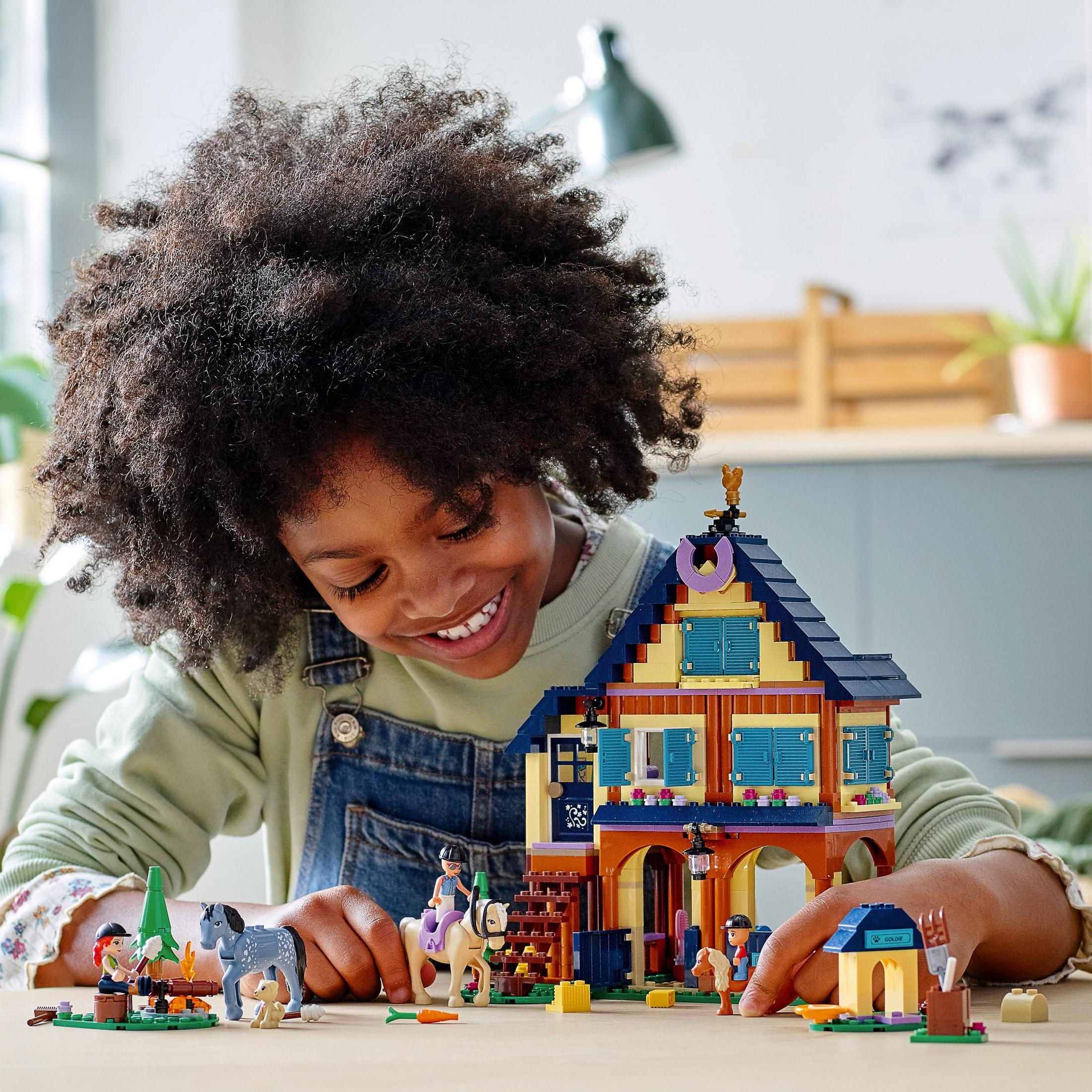 Zestaw Lego z domem, dziewczynką na koniu i innymi figurkami.