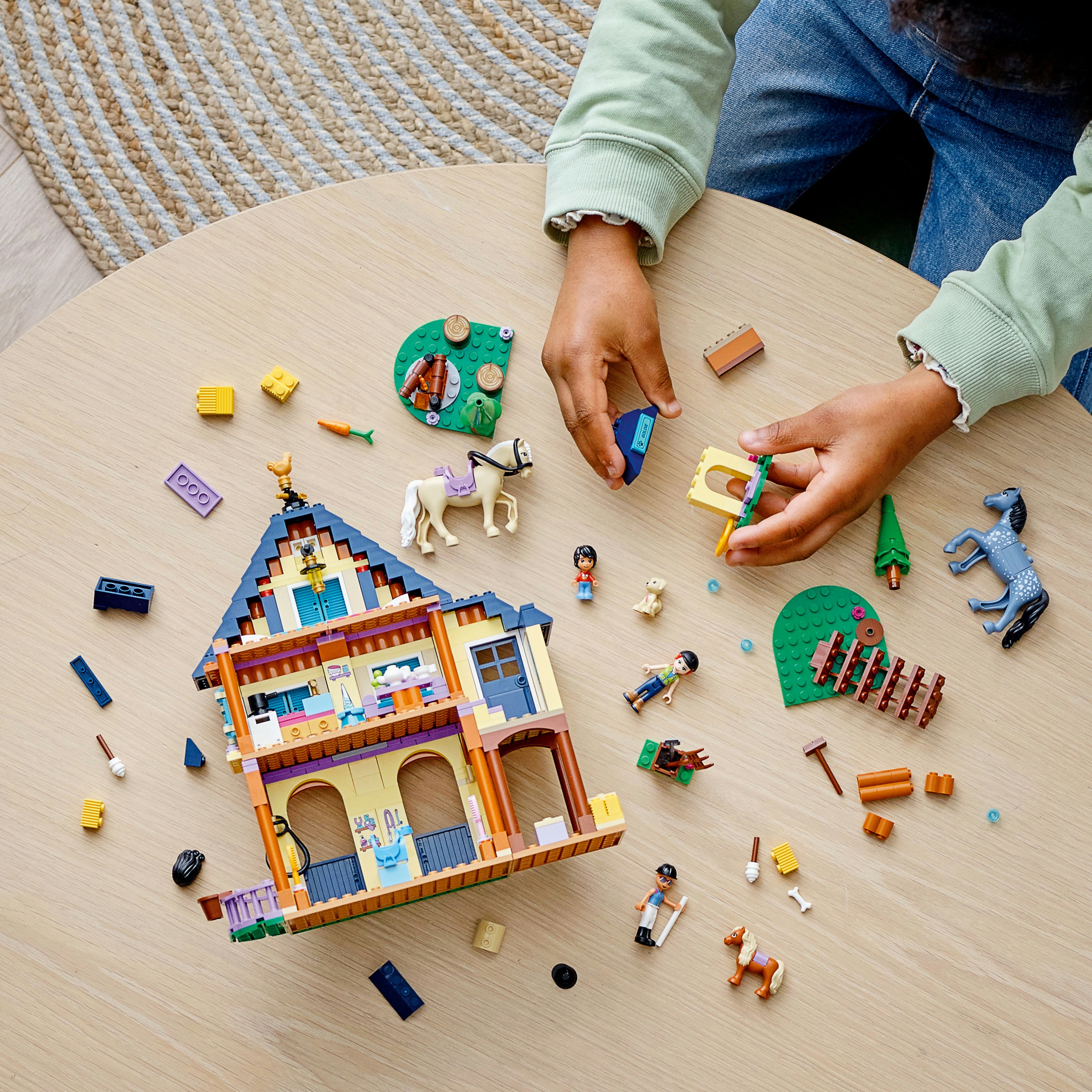 Dziecko bawiące się zestawem Lego Friends. Dom, akcesoria i figurki na stole.