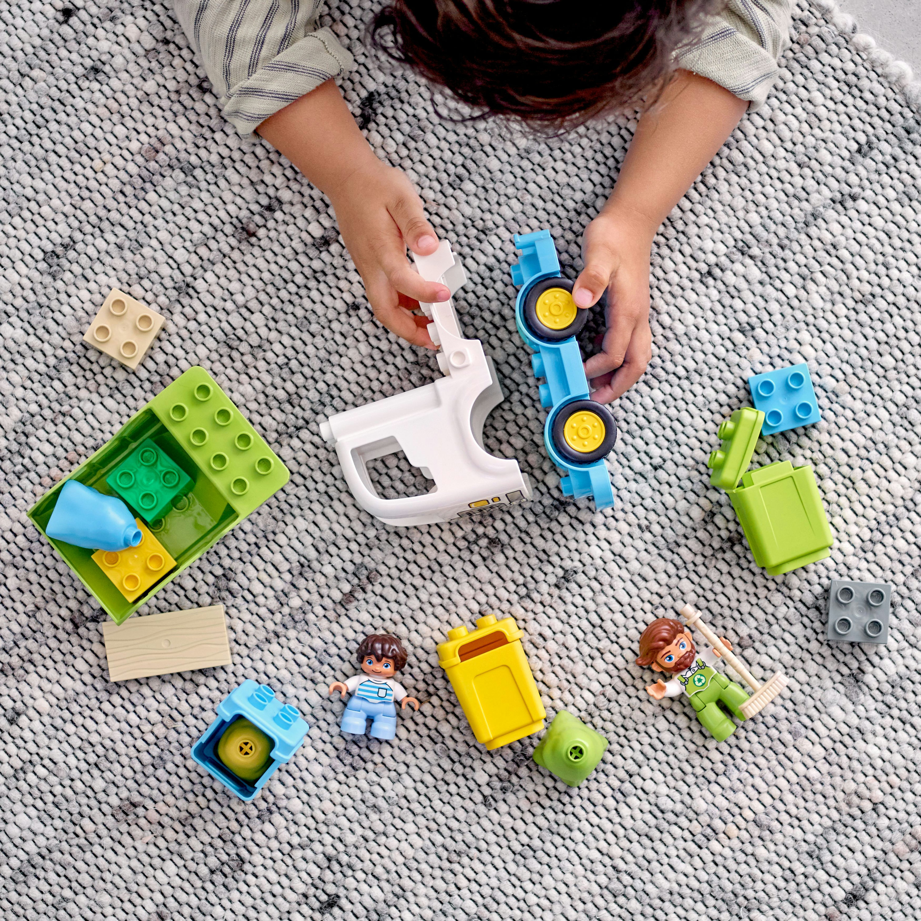 Un niño juega con bloques de Lego, incluyendo un camión azul y figuras de Lego.