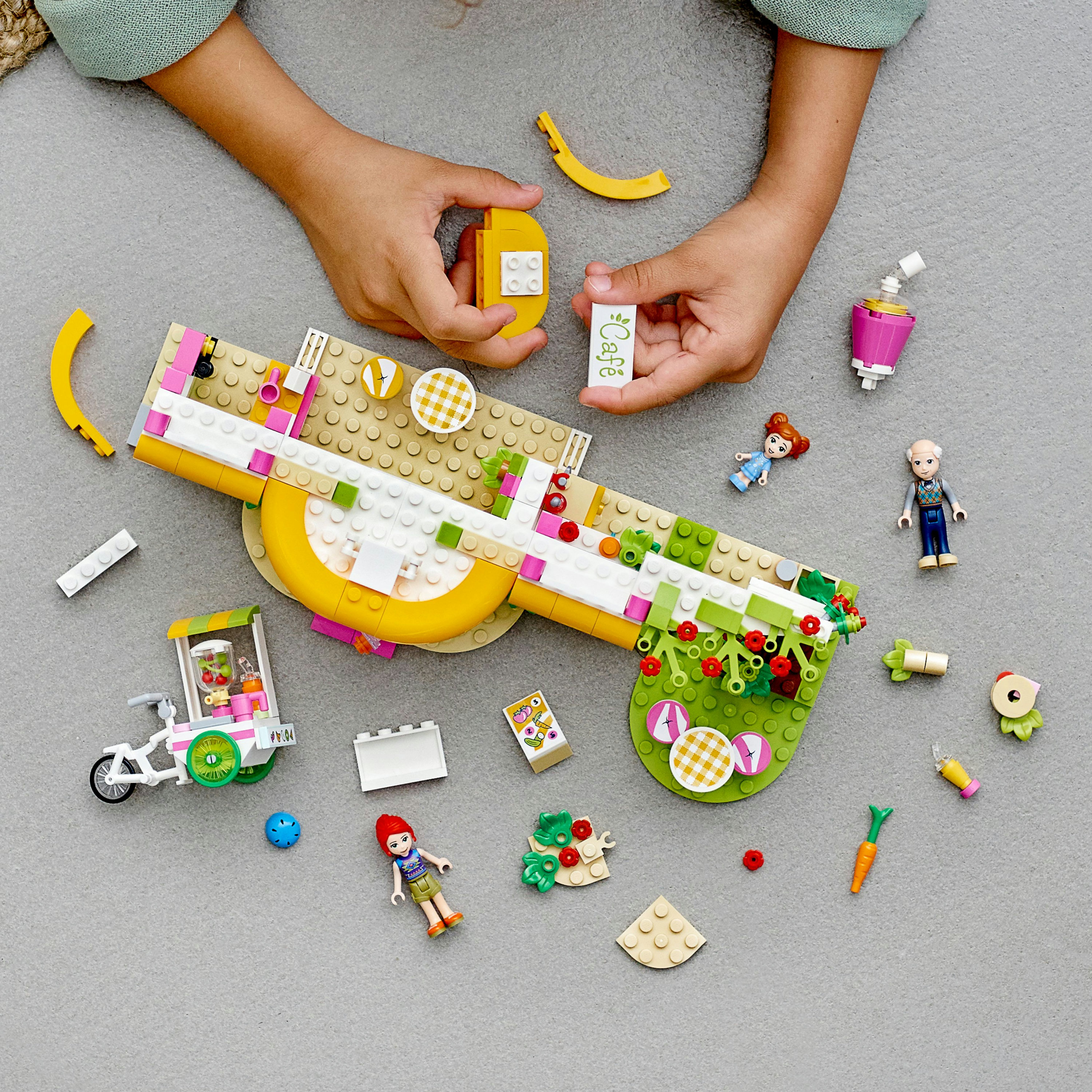 Bambino che gioca con set LEGO Friends. Scena a tema caffè con figure.