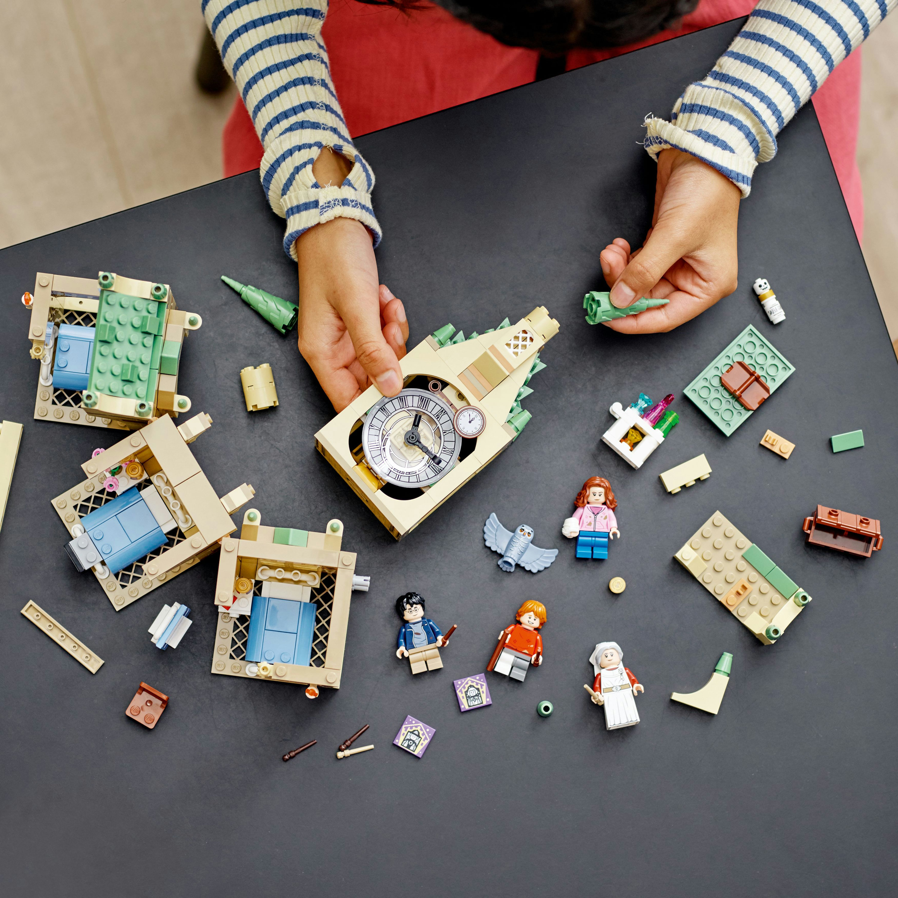 Lego-Set mit Lego-Figuren und Zubehör auf einem schwarzen Tisch. Hände bauen.