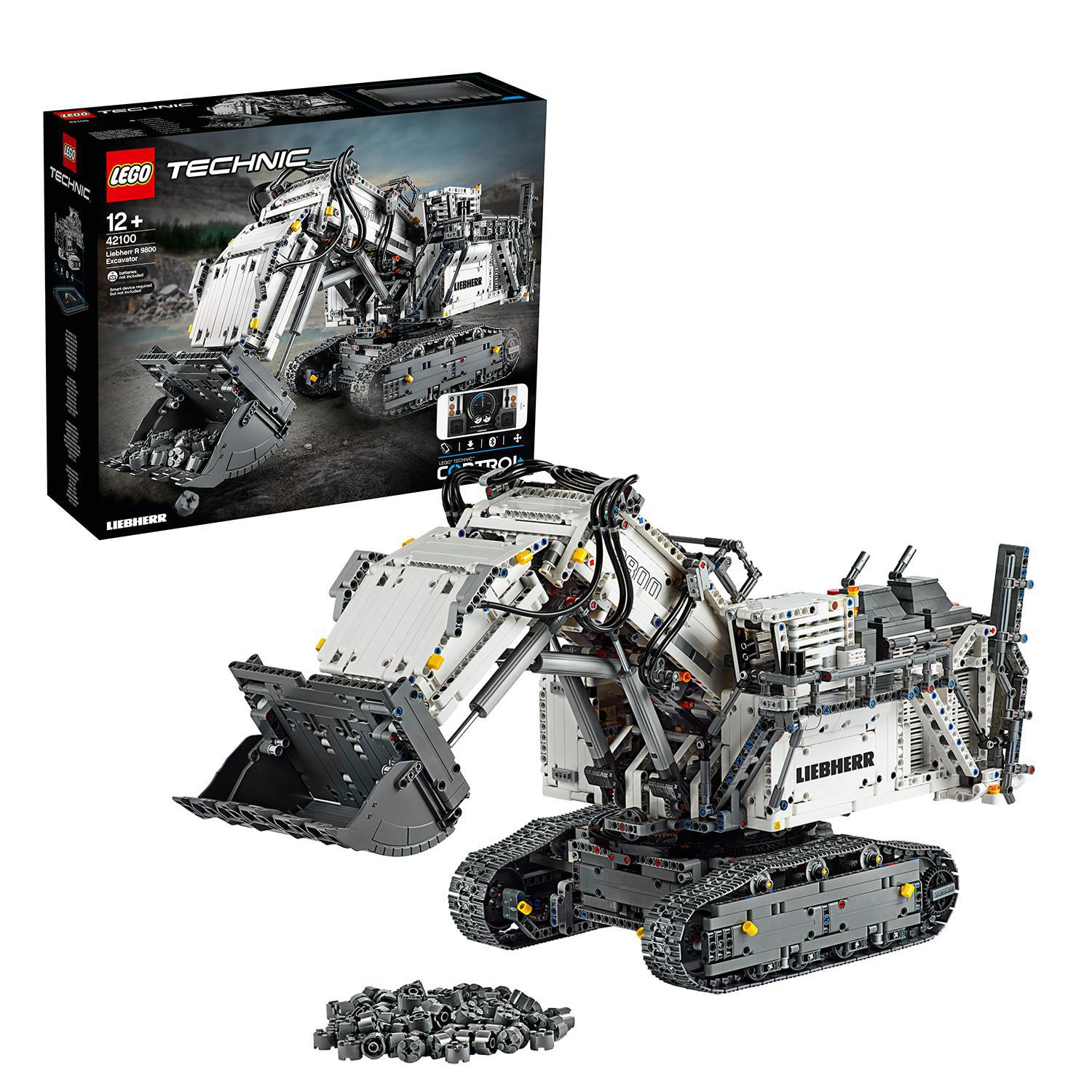 Model koparki Lego Technic z czarnym pudełkiem. Biała i szara koparka, czarne gąsienice i stos szarych elementów.