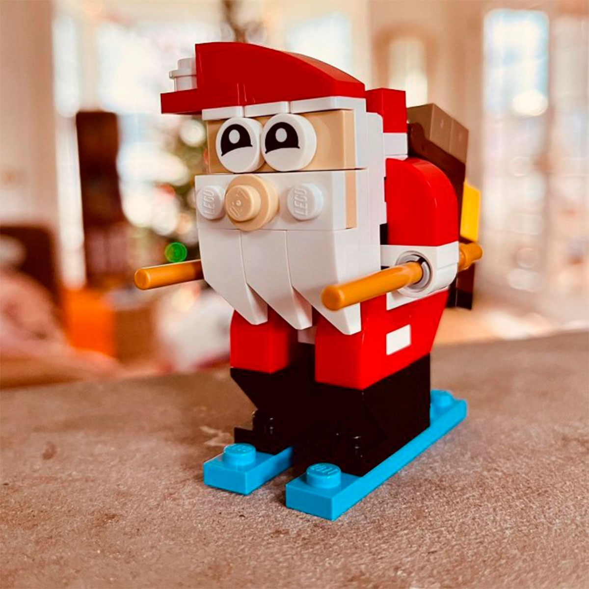 Figurka Lego Świętego Mikołaja na powierzchni. Jest czerwony, biały i czarny. Ma białą brodę i czerwony kapelusz.