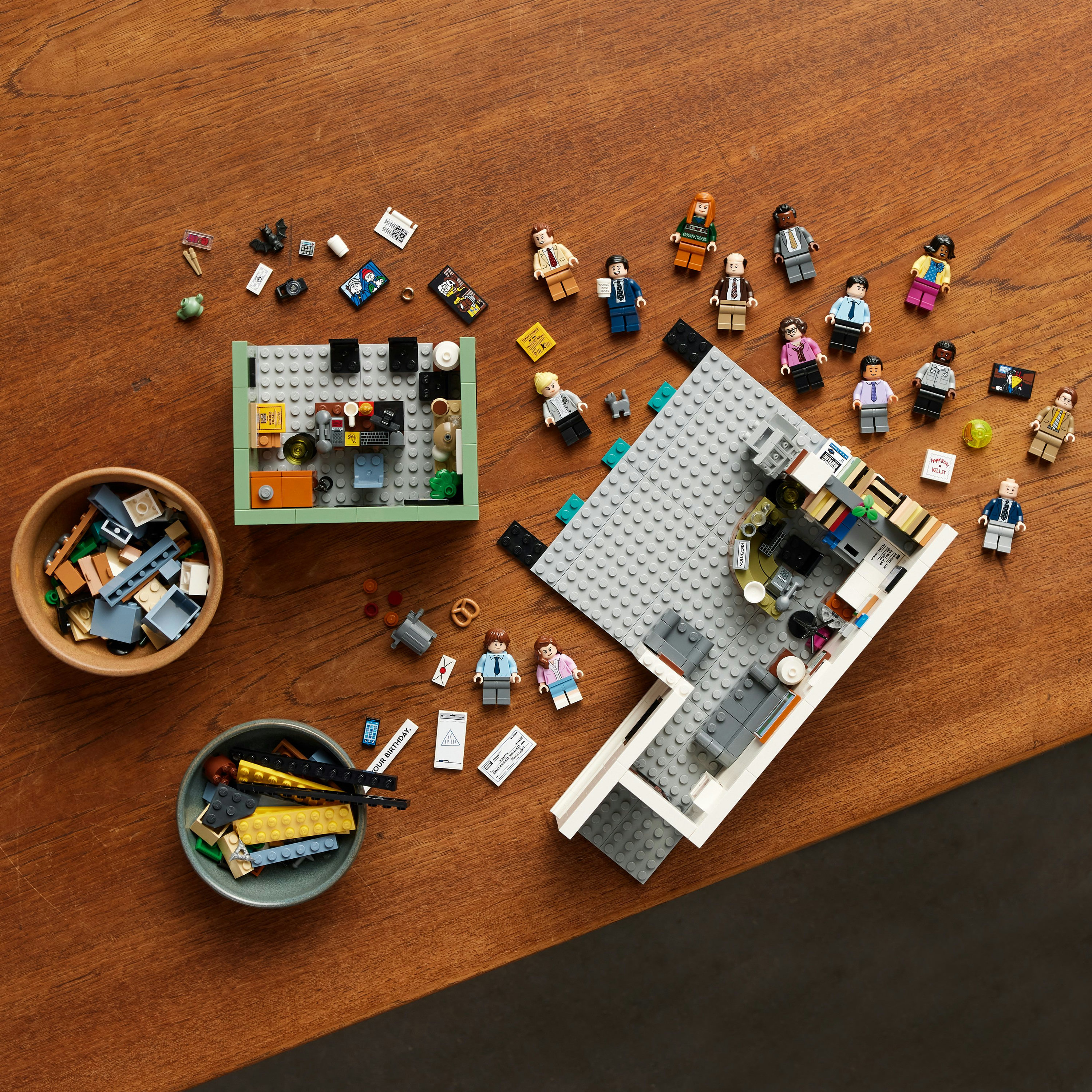 Lego set with office scene and figurines on a wooden table.