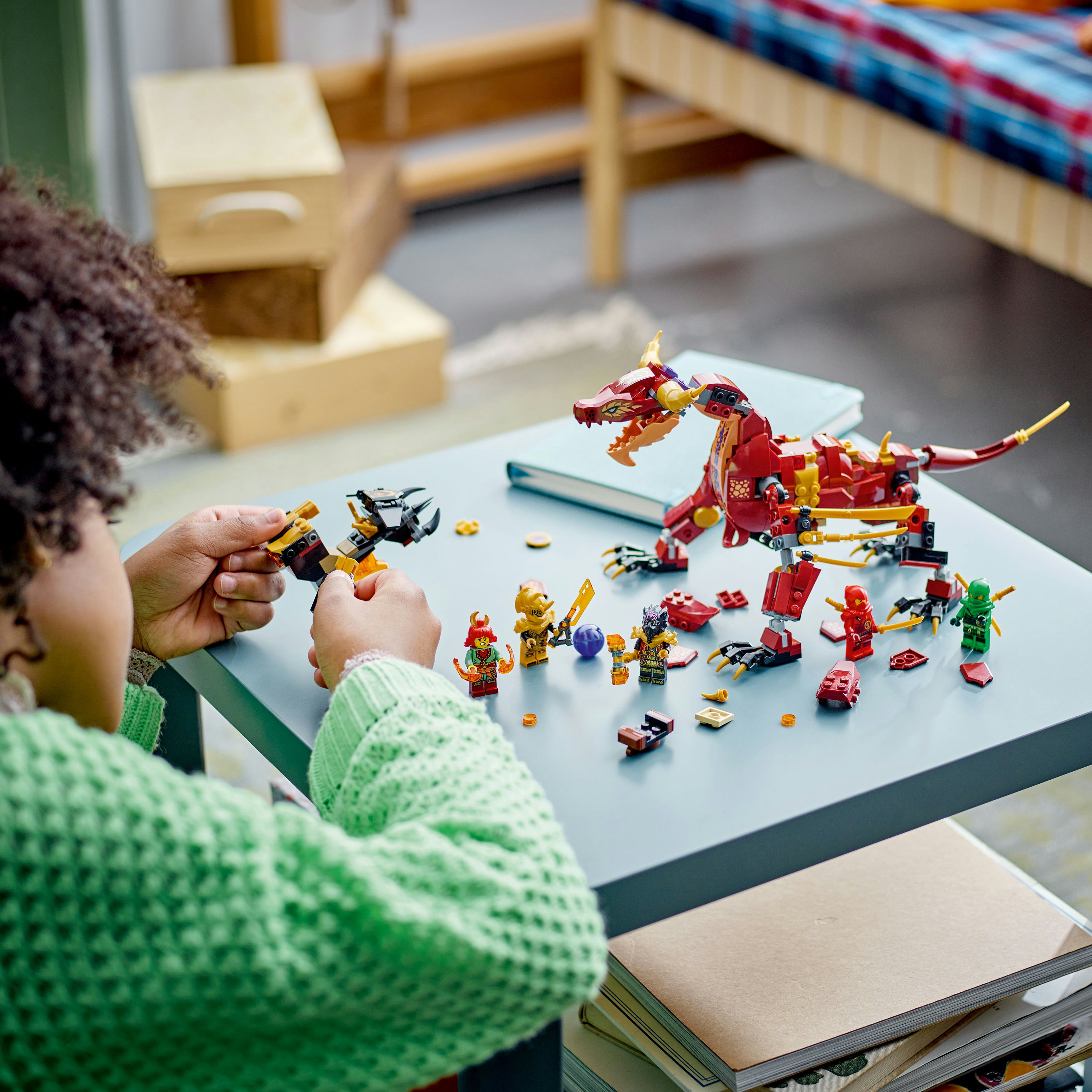 Ein Kind spielt mit LEGO Ninjago Set, roter Drache, Minifiguren und verschiedenen LEGO Teilen.