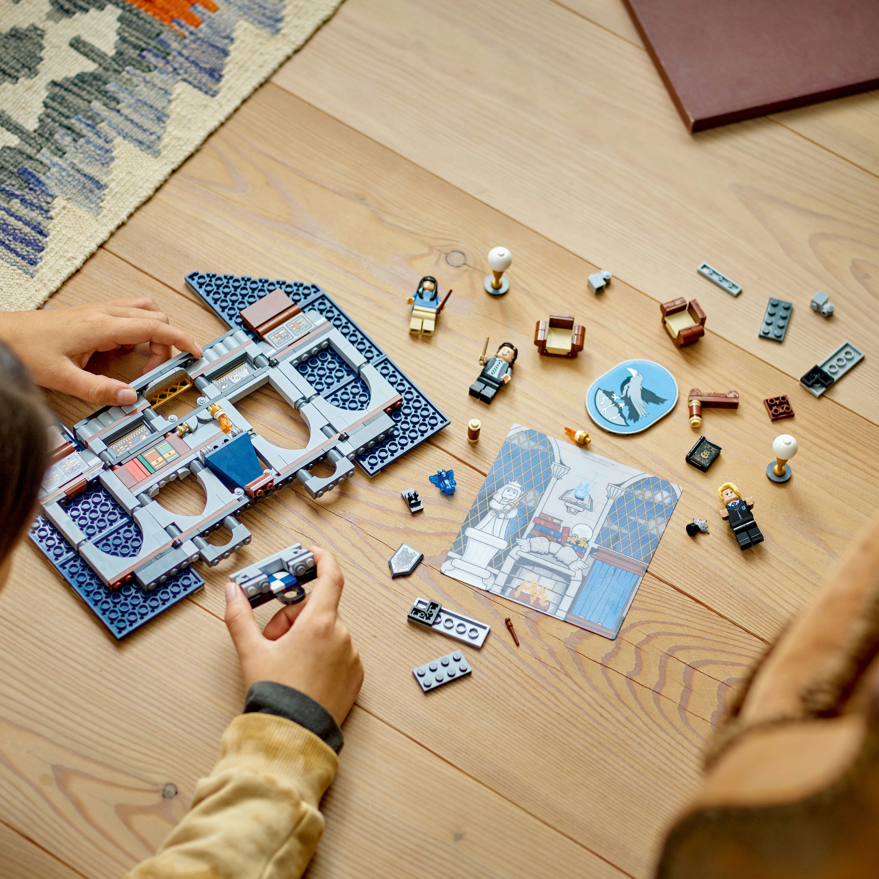 Ein Lego-Set wird auf einem Holztisch zusammengebaut. Lego-Teile und Figuren sind verstreut.