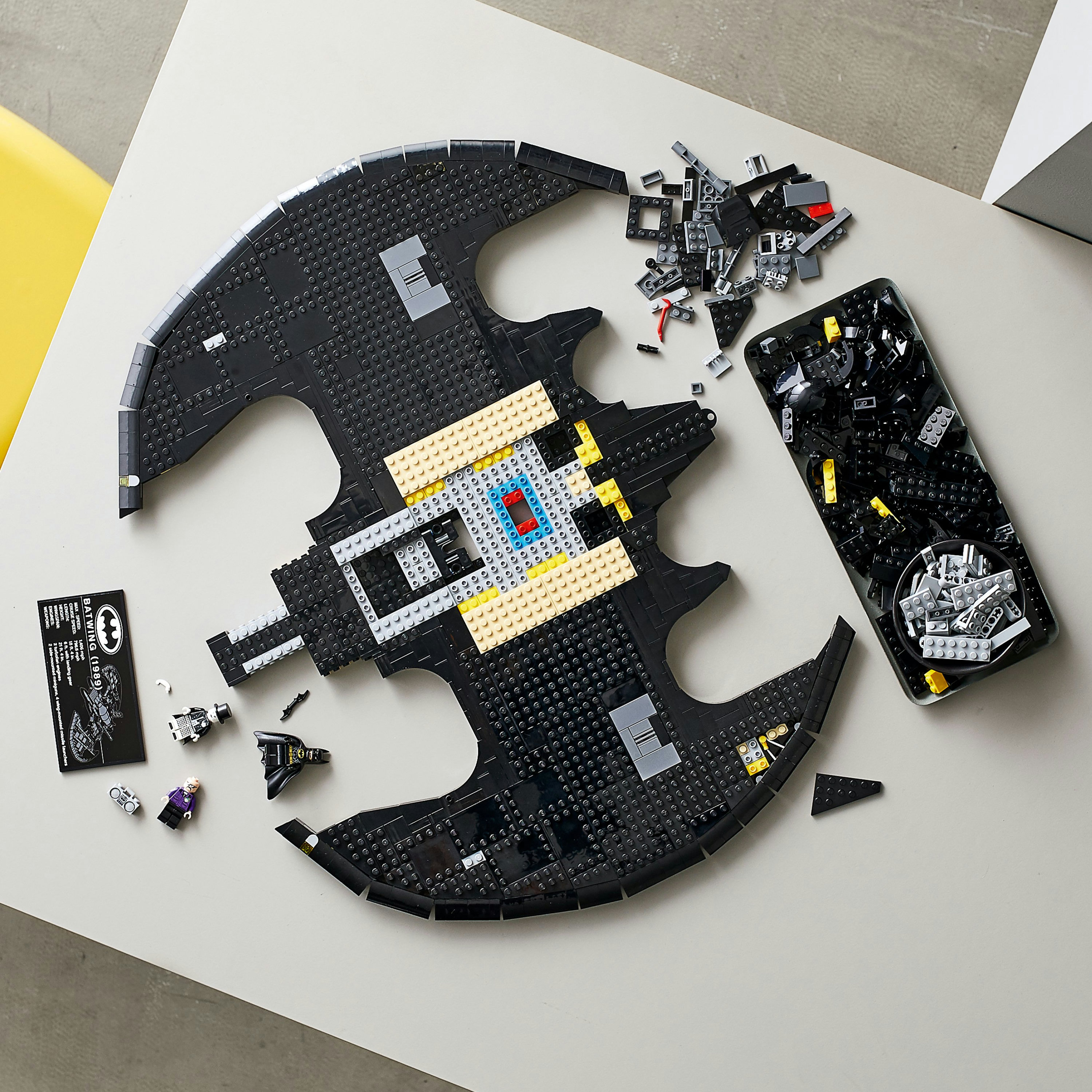 Zdemontowany zestaw LEGO Batman na jasnoszarym stole, z rozrzuconymi elementami.