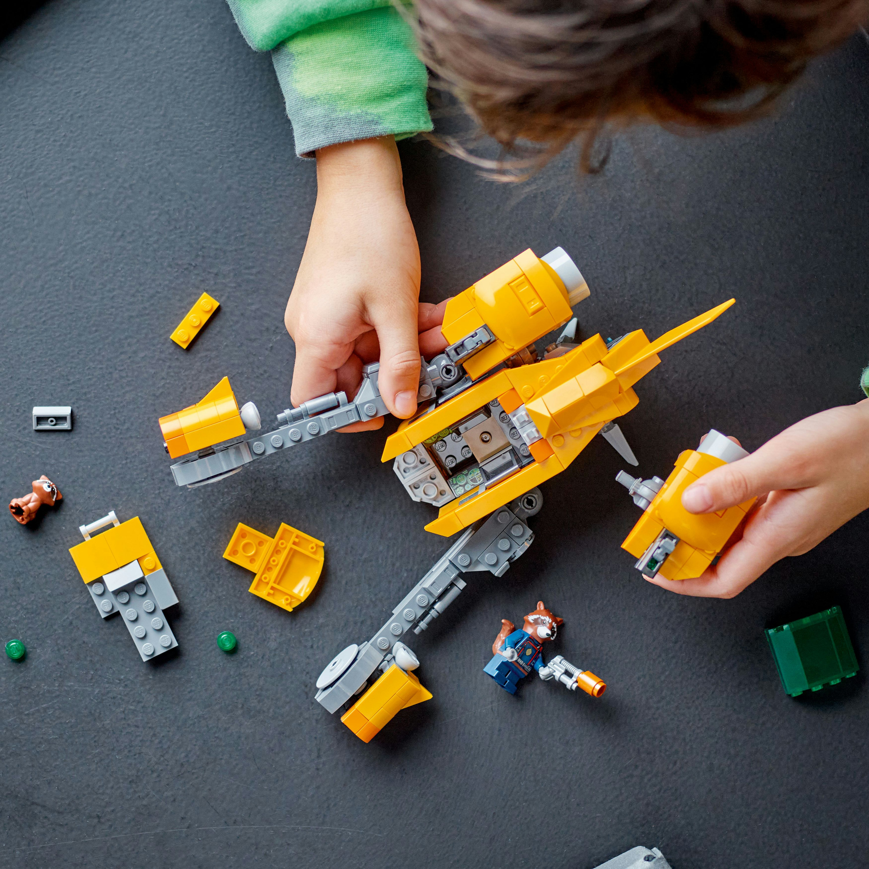 Kind dat een Lego ruimteschip in elkaar zet, met onderdelen en de Rocket figuur zichtbaar.