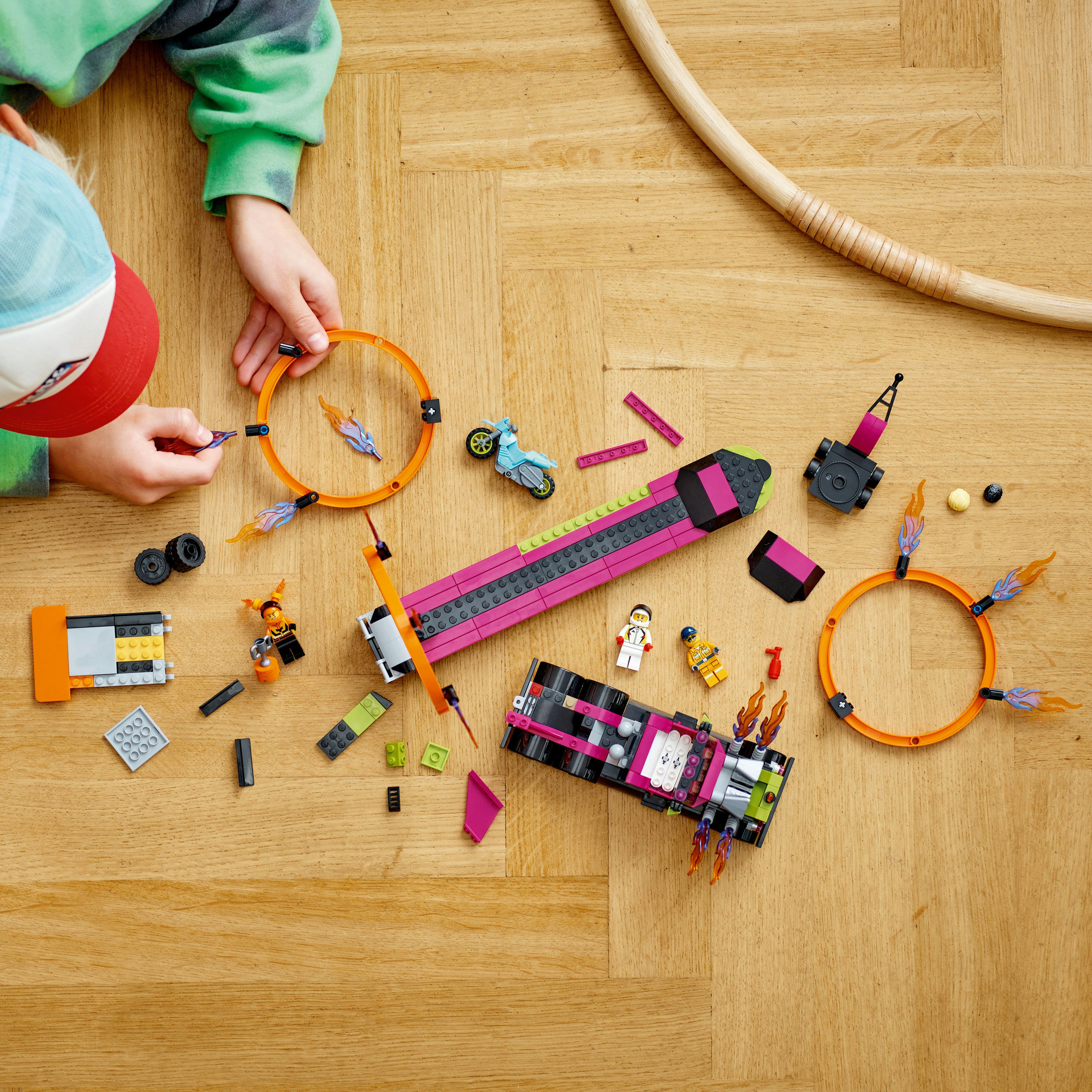 Bambino che gioca con i giocattoli da costruzione Lego. Vari pezzi Lego su un pavimento in legno.