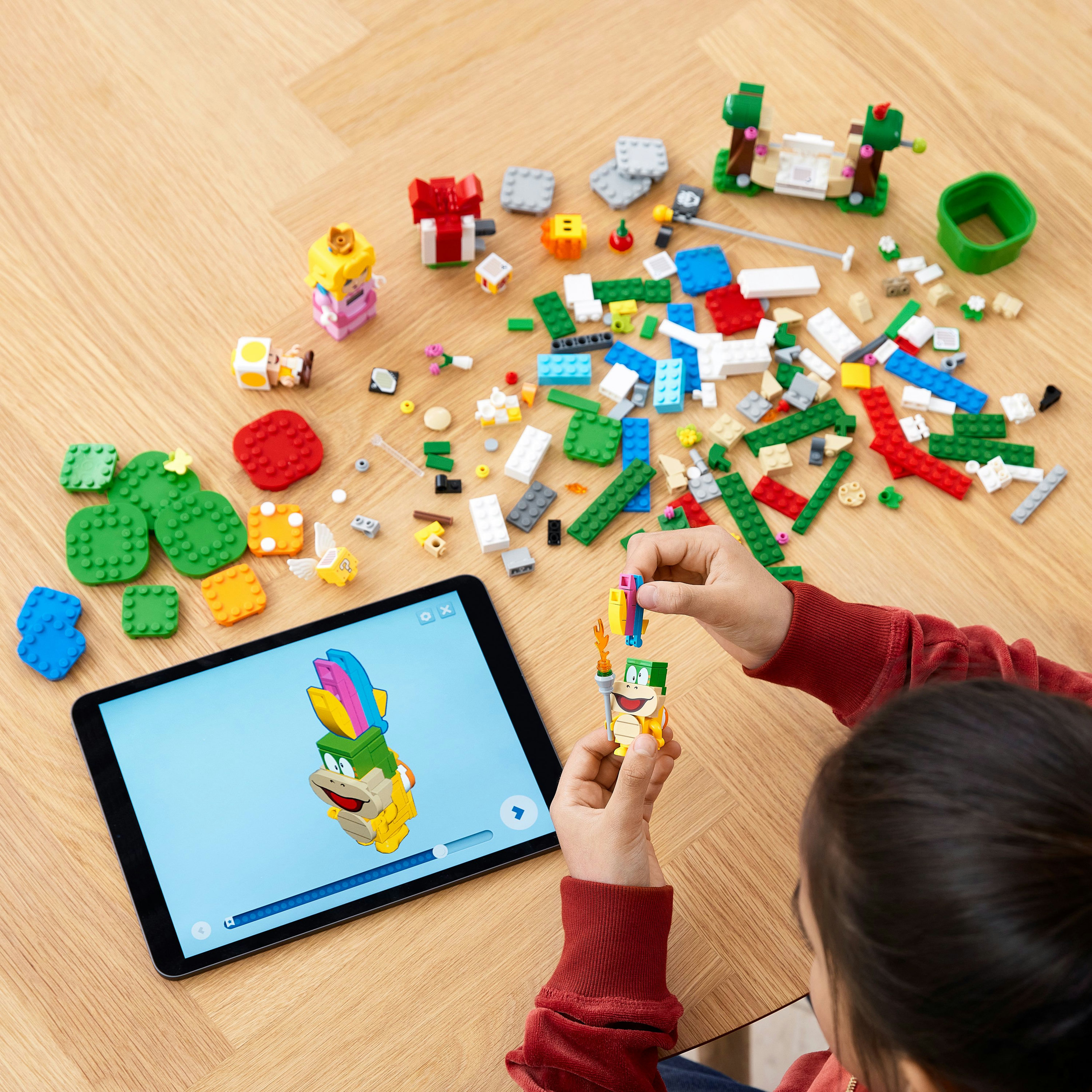 Een kind dat Lego in elkaar zet met een tablet met de Lego-instructies.