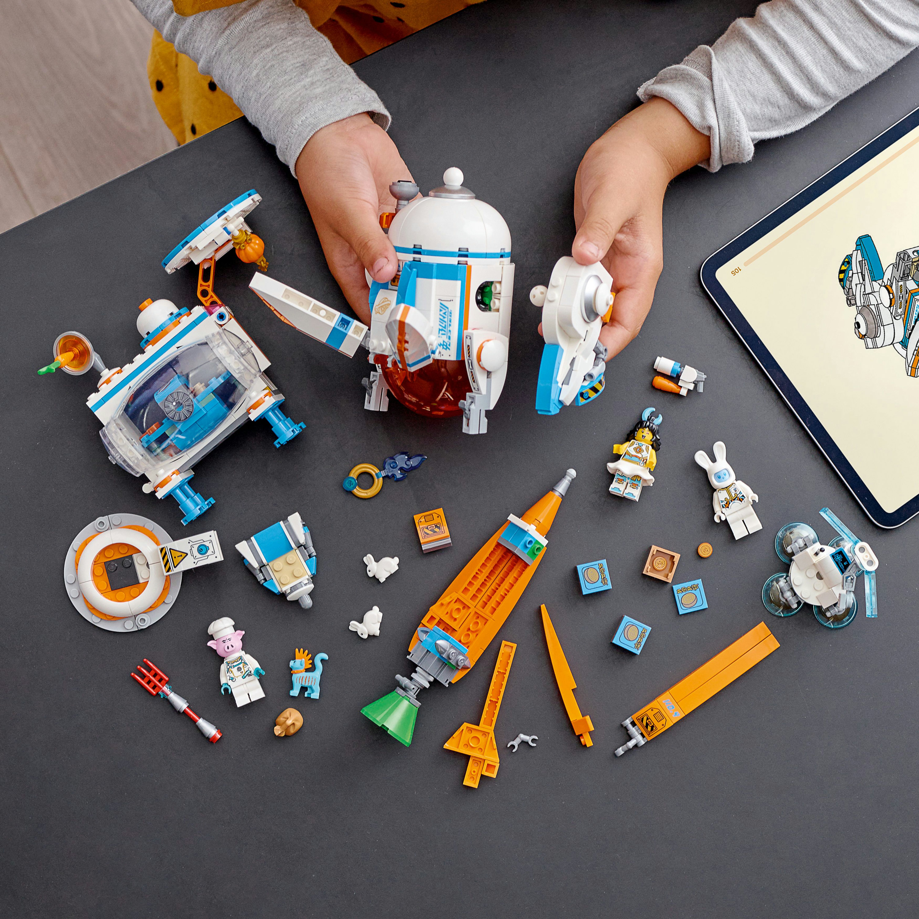 Karanlık bir yüzeyde uzay temalı bir setle Lego parçalarını düzenleyen bir çocuğun elleri.