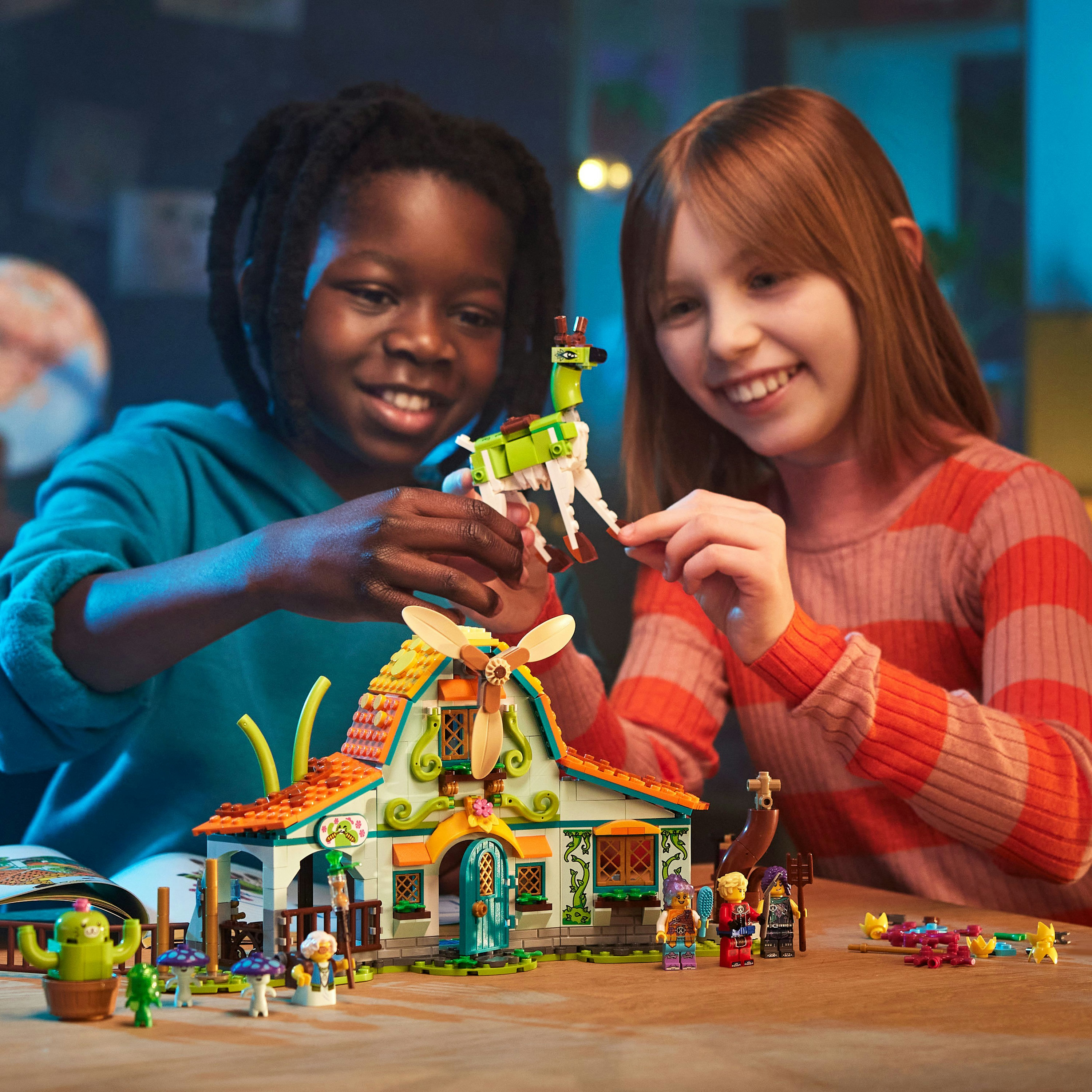 Zwei Kinder bauen ein Lego-Haus mit einem grünen Lama, glücklich und lächelnd.