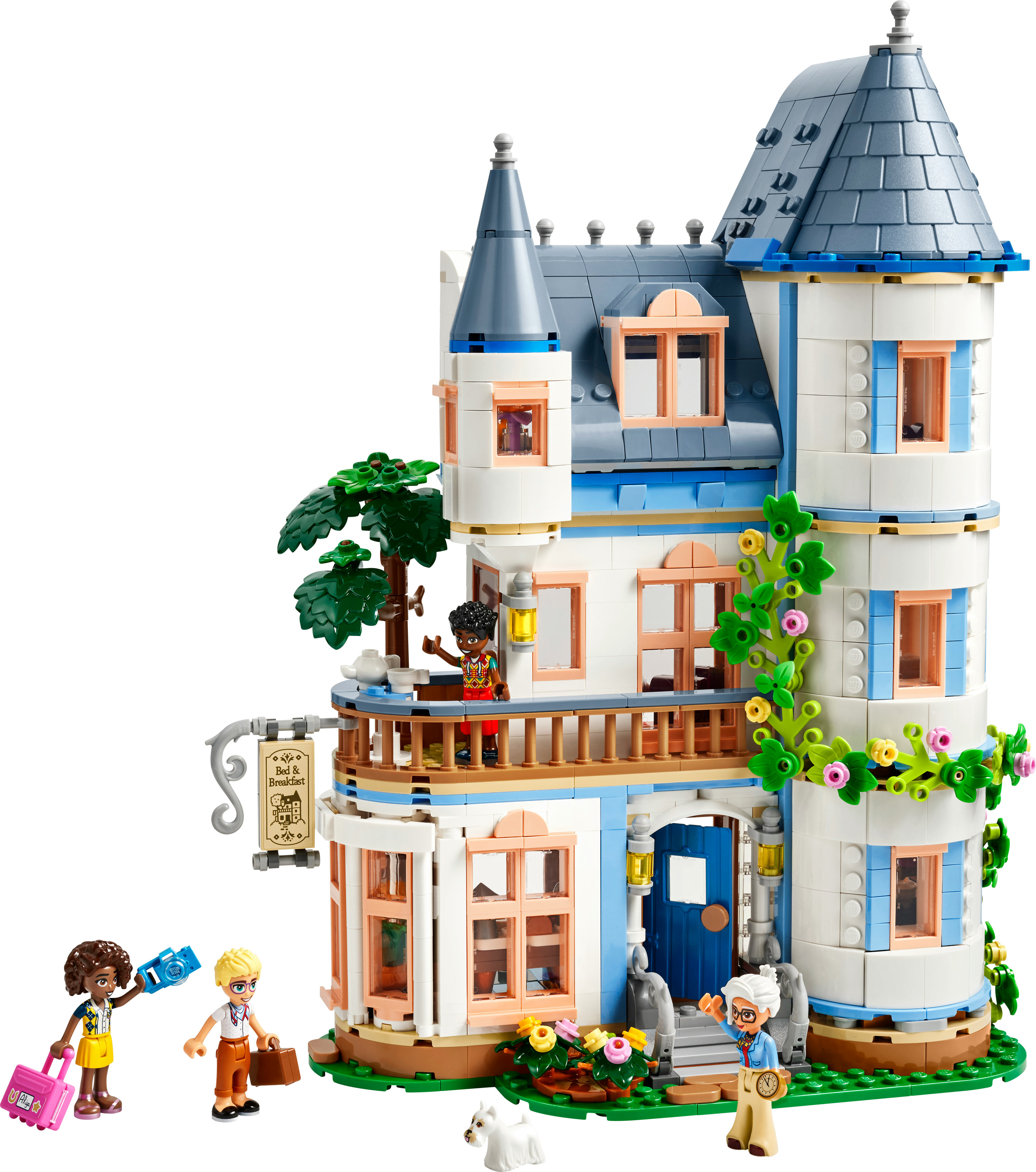 Lego Friends set: een wit en blauw gebouw met figuren van mensen en een hond. Bomen en bloemen zijn aanwezig.