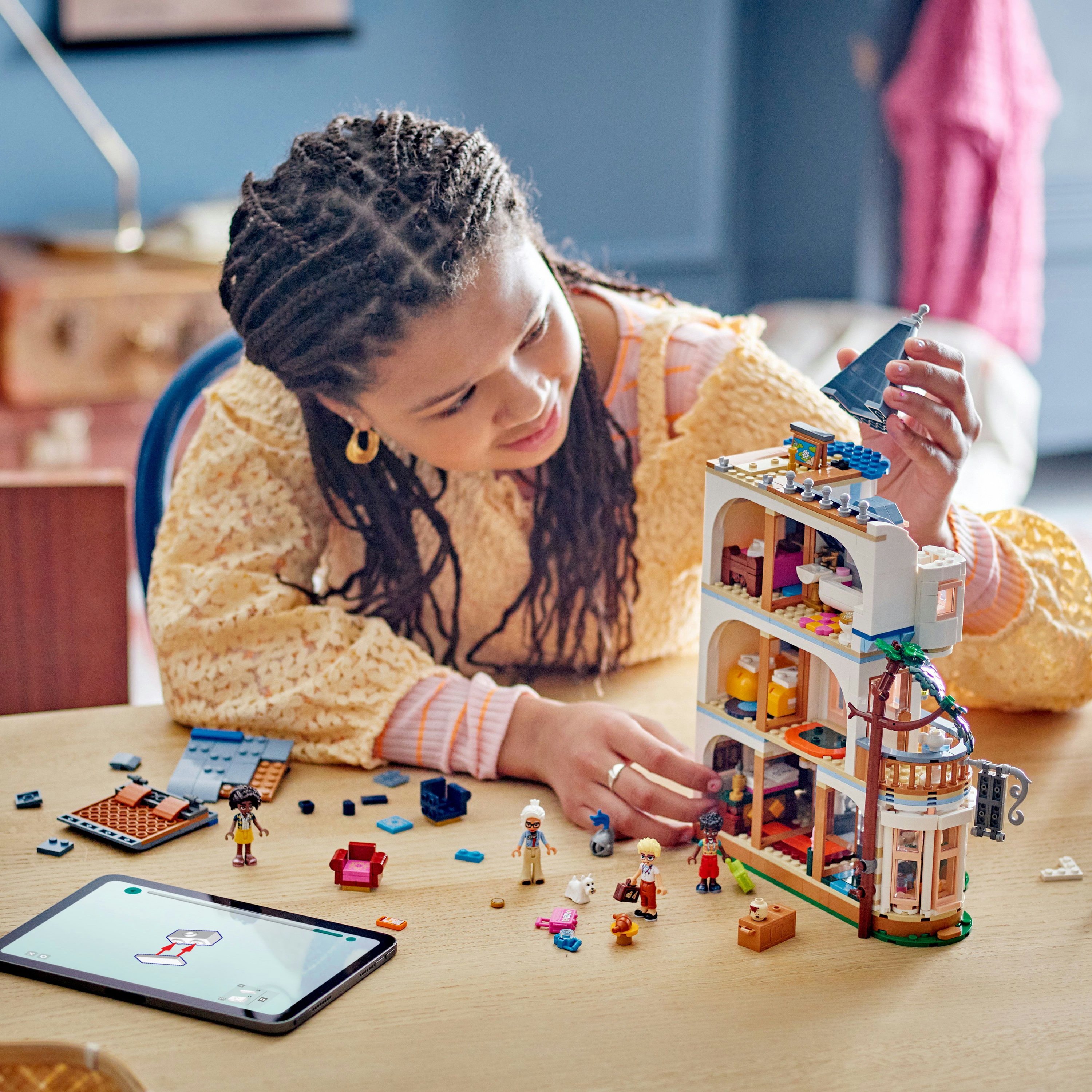 Een persoon die een Lego-gebouwmodel in elkaar zet met een tablet en diverse Lego-stukken.
