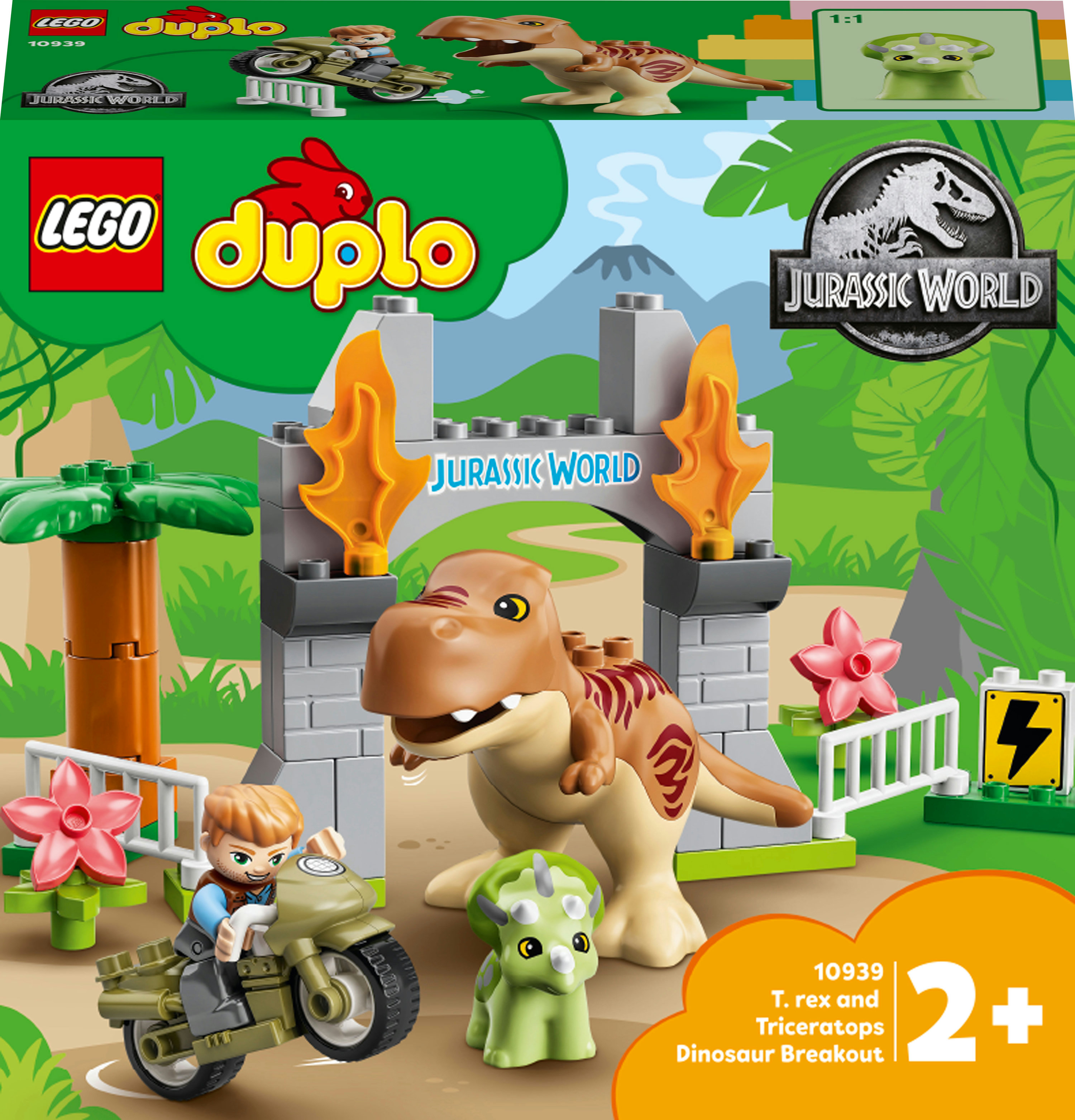 Scatola del set Lego Duplo. Un T-rex e un Triceratopo davanti a un cancello. Un ragazzo va in moto.