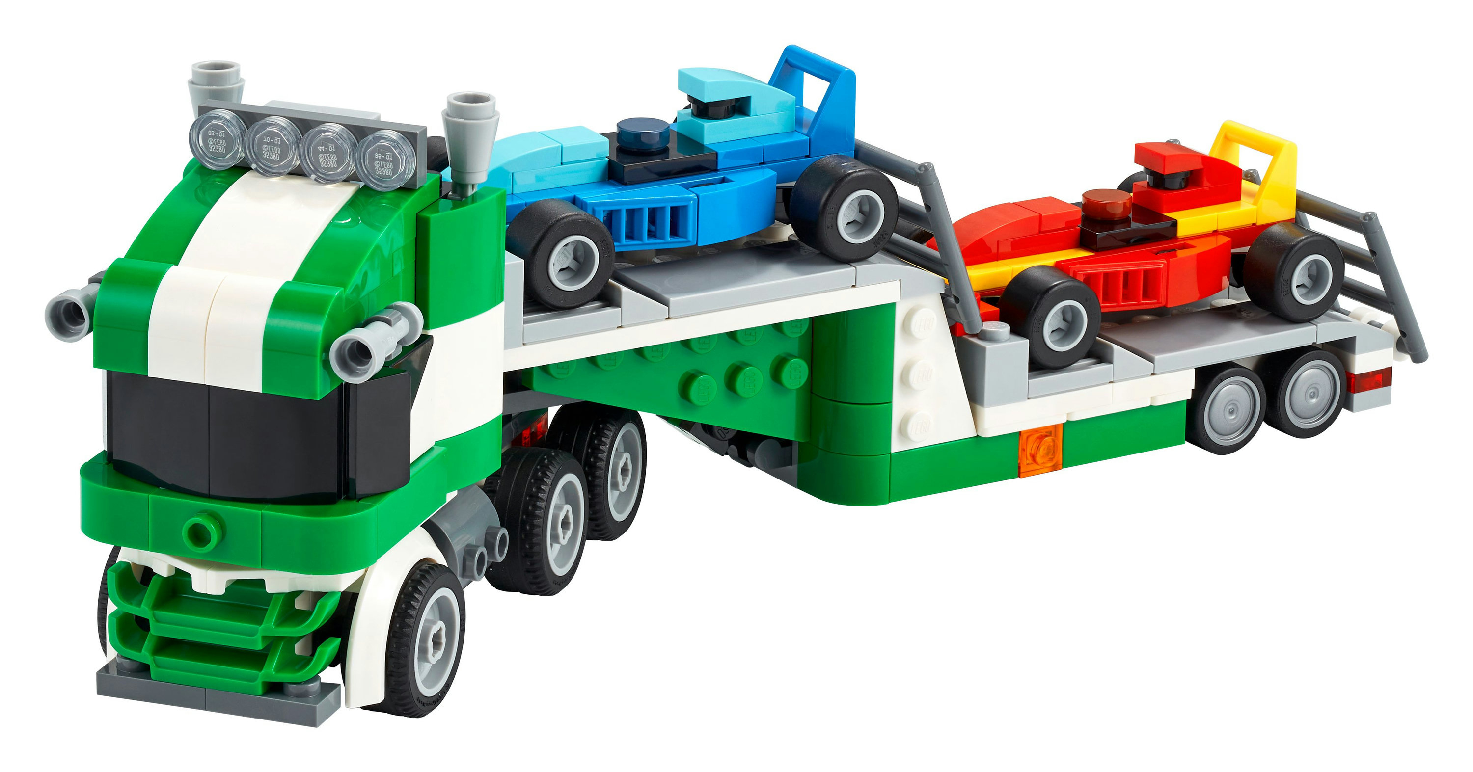 Ein grün-weißer LKW mit zwei Rennwagen auf seinem Anhänger. Einer blau, einer rot und gelb. Alles Lego.