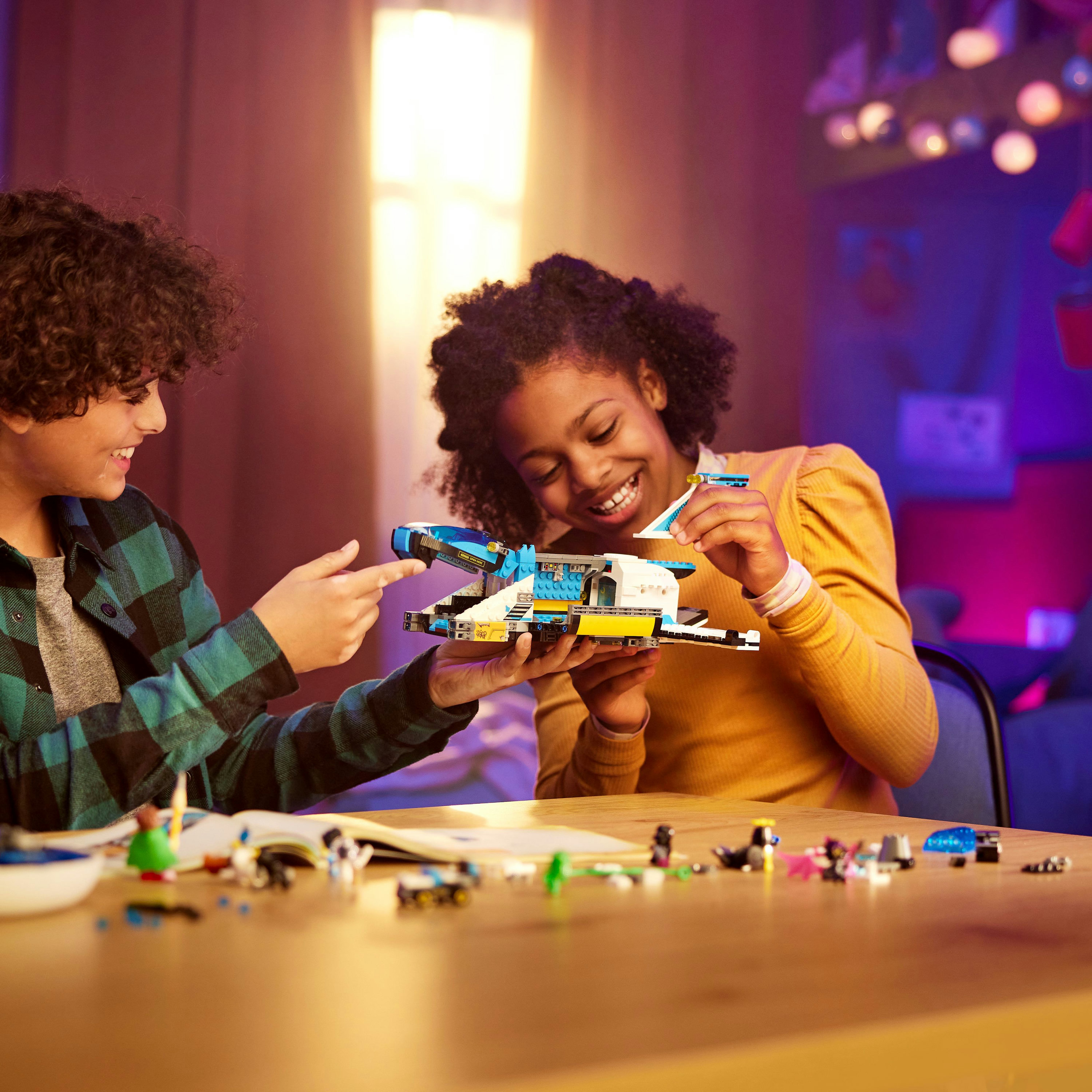Zwei Kinder bauen gemeinsam ein Lego-Raumschiff, mit Legosteinen auf einem Tisch.