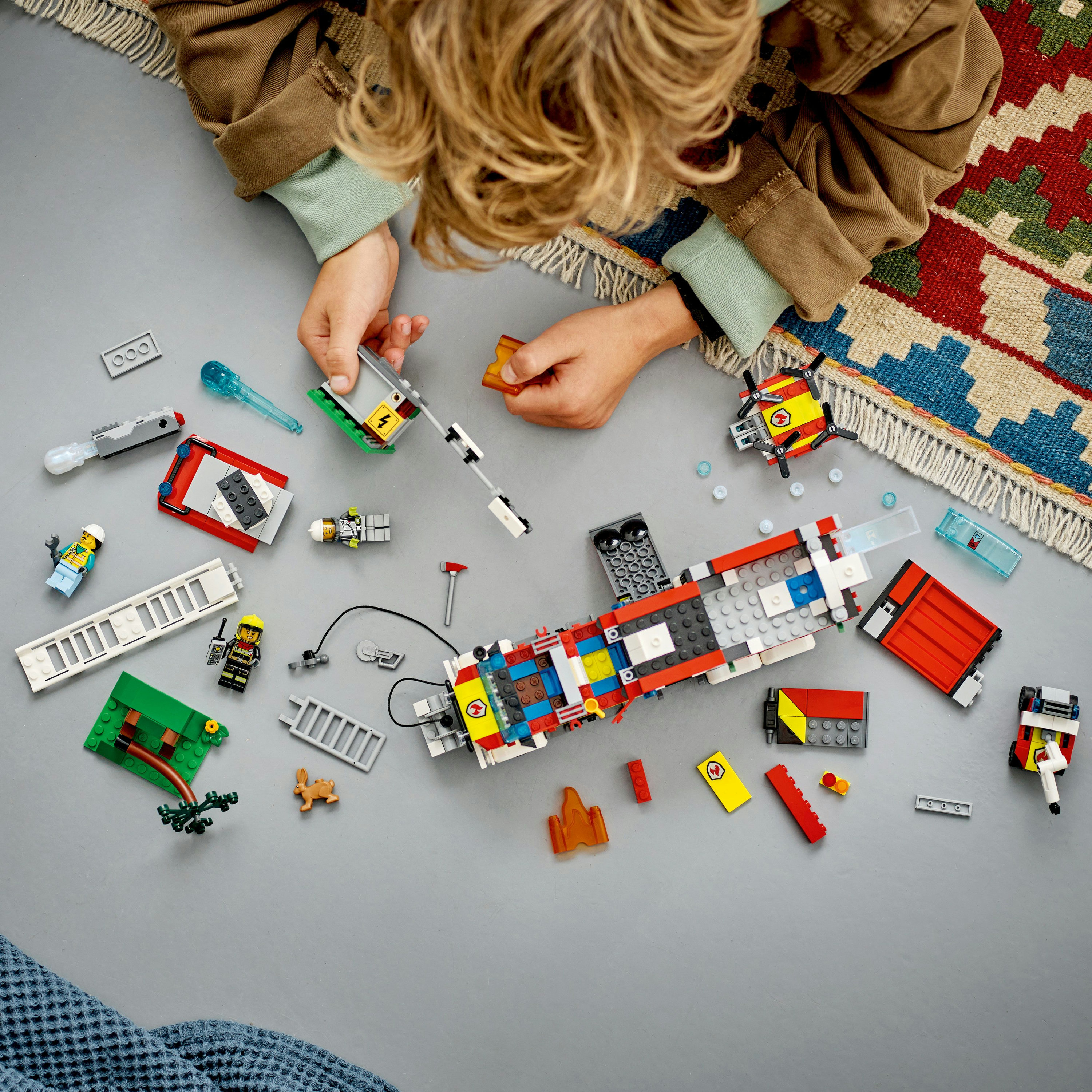 Çocuk Lego parçalarıyla oynuyor, çeşitli parçalar dağılmış.