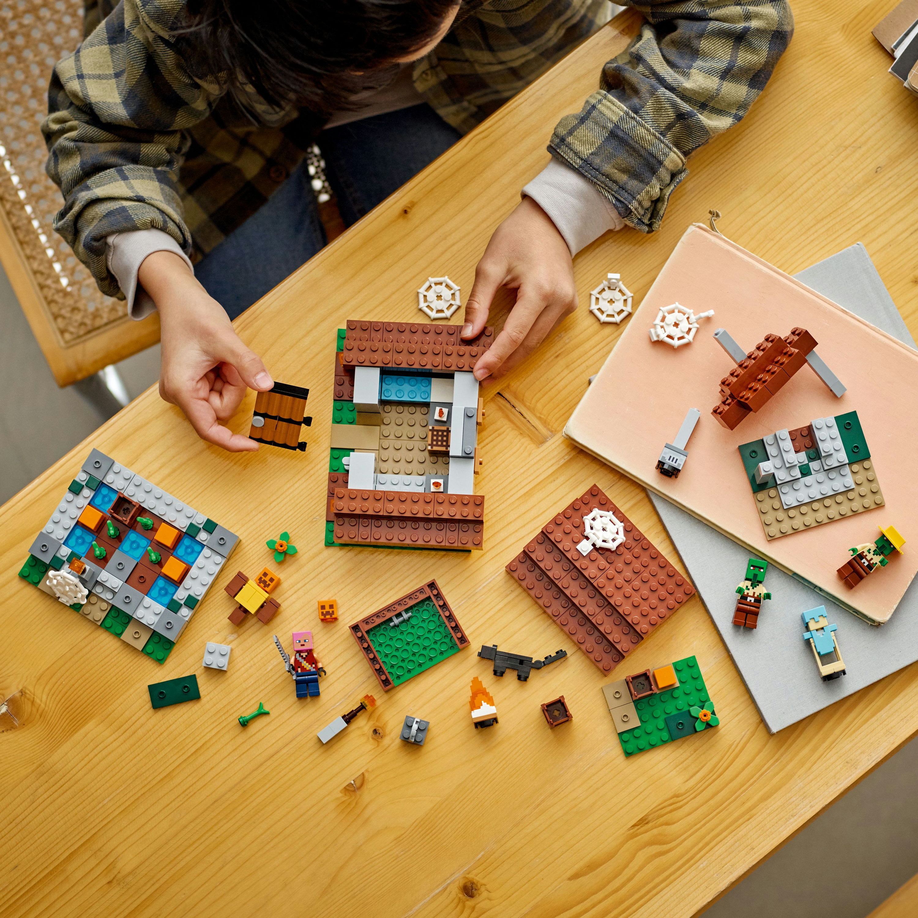 Ein Kind baut mit Lego-Steinen auf einem Holztisch, mit verschiedenen Teilen und fertigen Abschnitten.