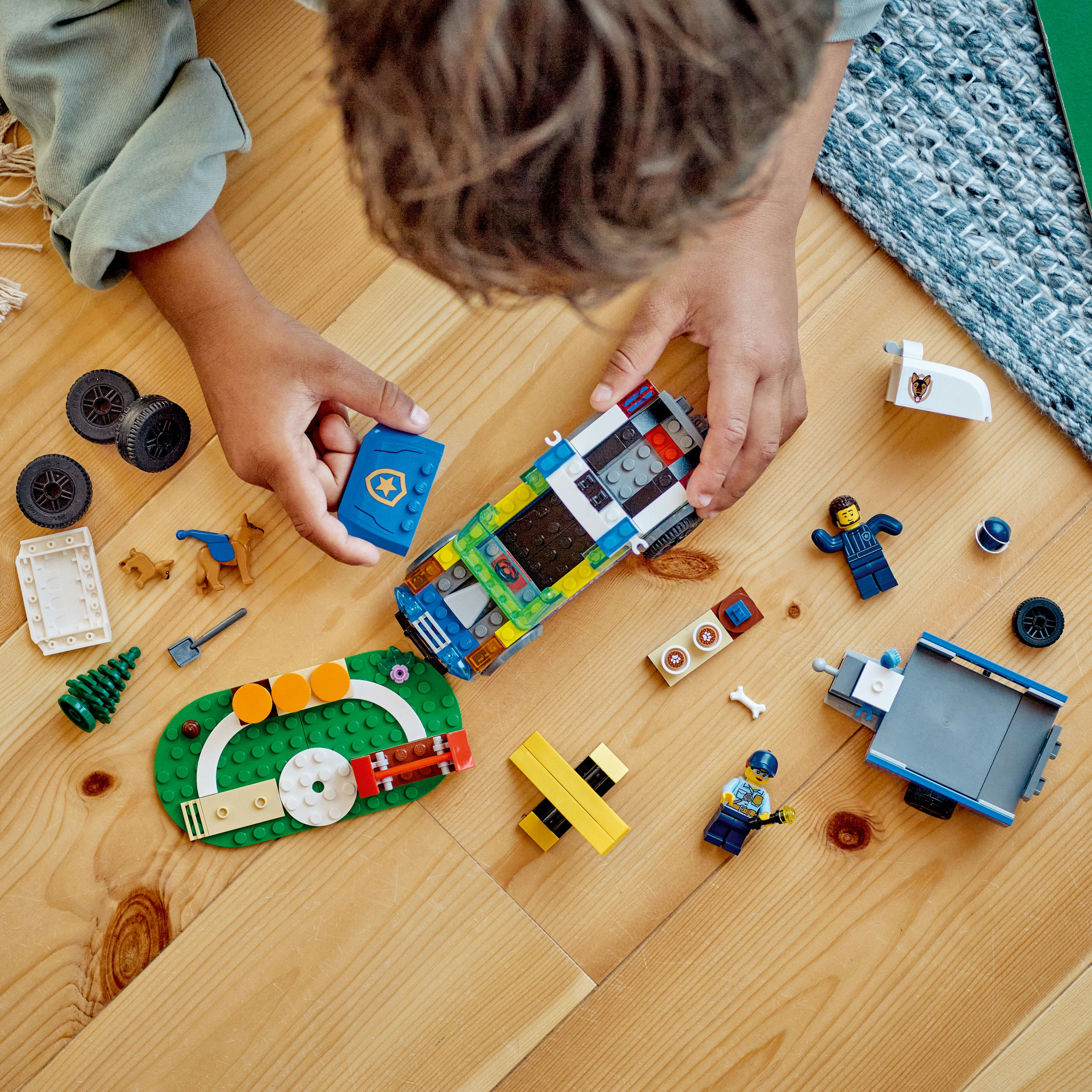Bir çocuk Lego parçalarıyla oynuyor. Bir araba ve diğer Lego eşyaları var.